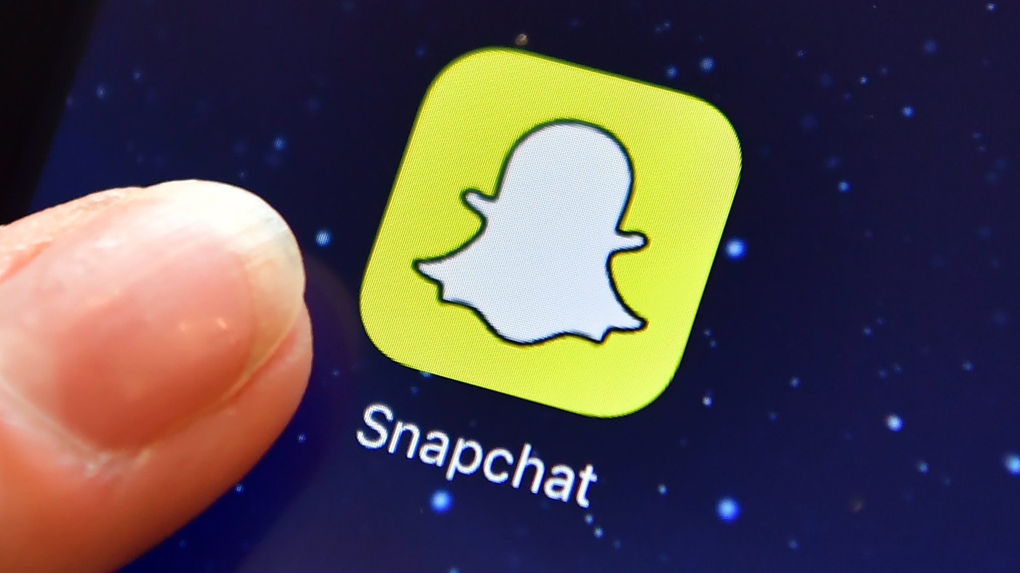 A finger is posed next to the Snapchat app logo on an iPad on August 3, 2016 in London, England