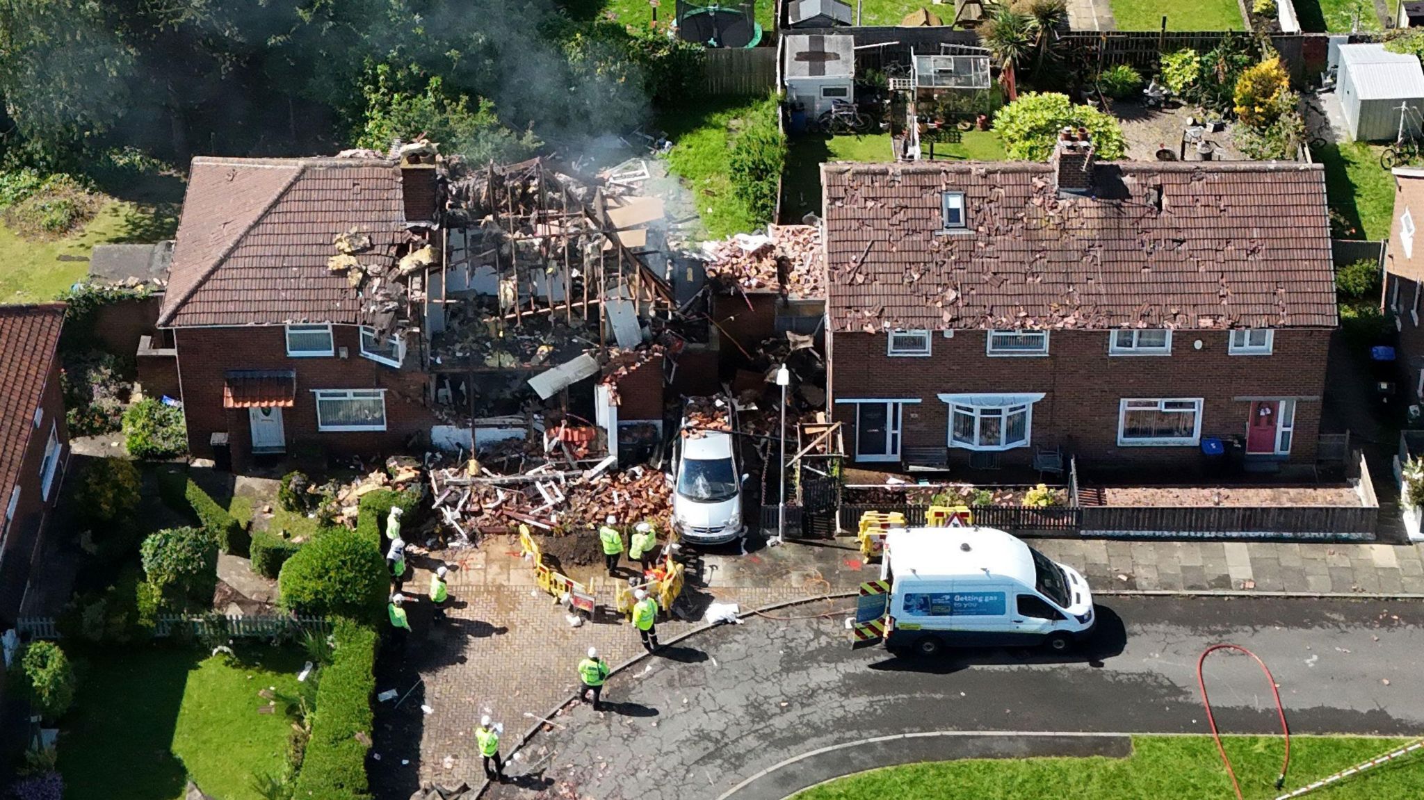 The scene of the explosion showing damage to a neighbouring property and gas engineers at work