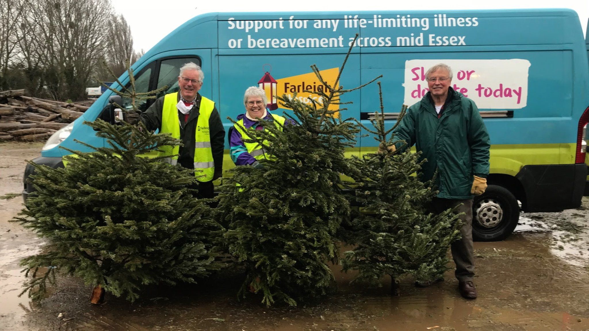 Farleigh Hospice staff standing in front of a van along with some of the donated Christmas trees.