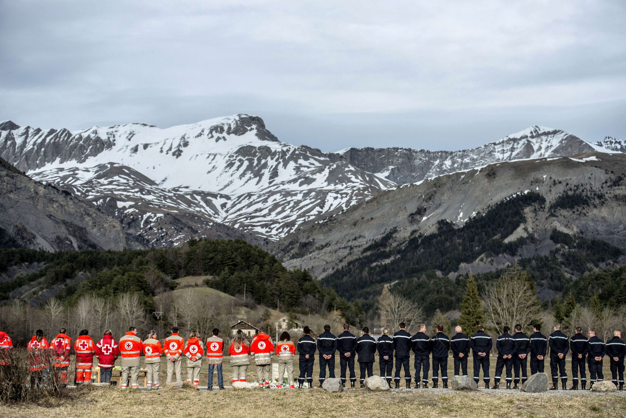 French rescue workers gather in front of a memorial for the victims of the Germanwings air crash in Le Vernet, south-eastern France, on March 28, 2015