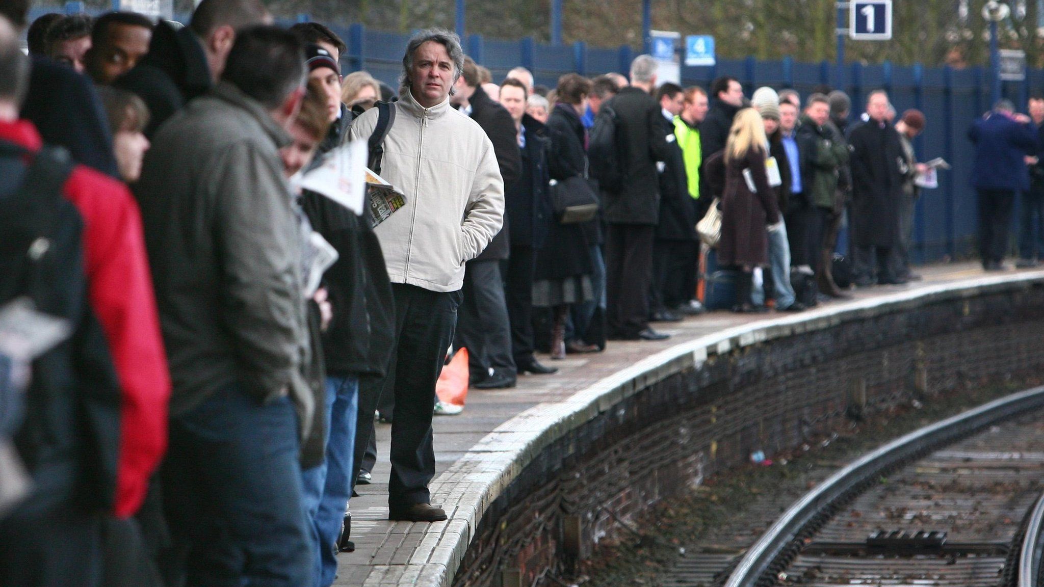 Commuters wait on a railway platform