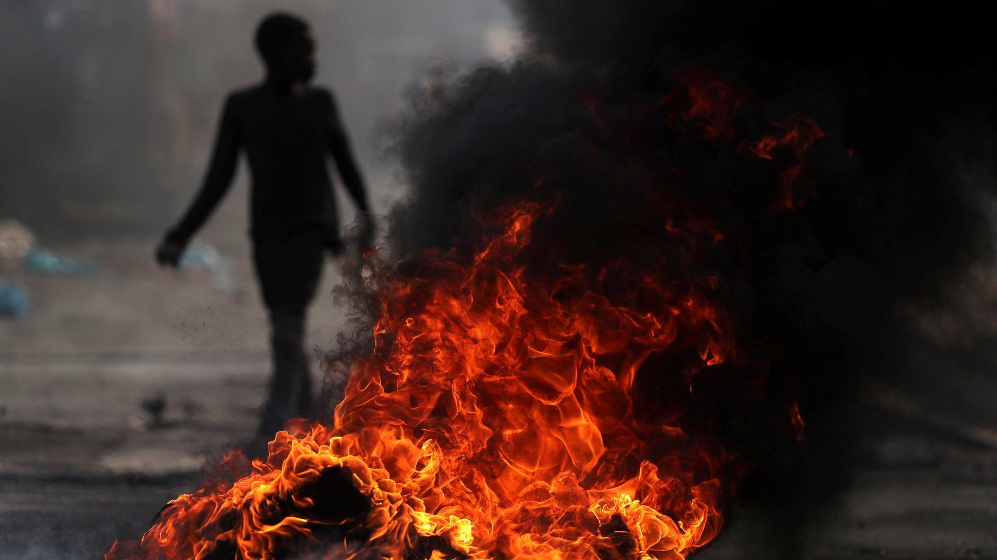 A child walks past a burning barricade during anti-government protests in Port-au-Prince