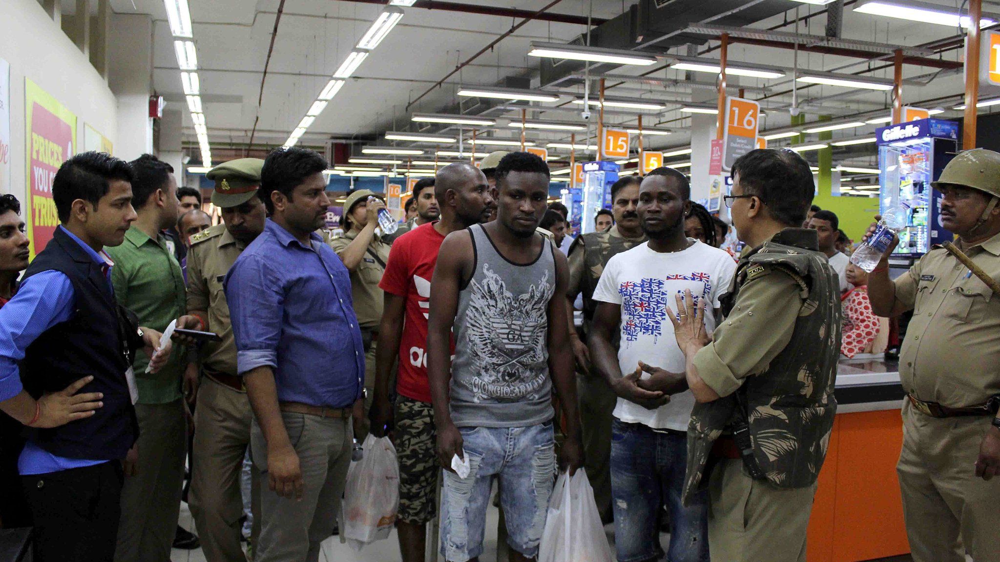 This photo taken on 27 March 2017 shows Indian police and onlookers surrounding African nationals at a shopping mall in Greater Noida