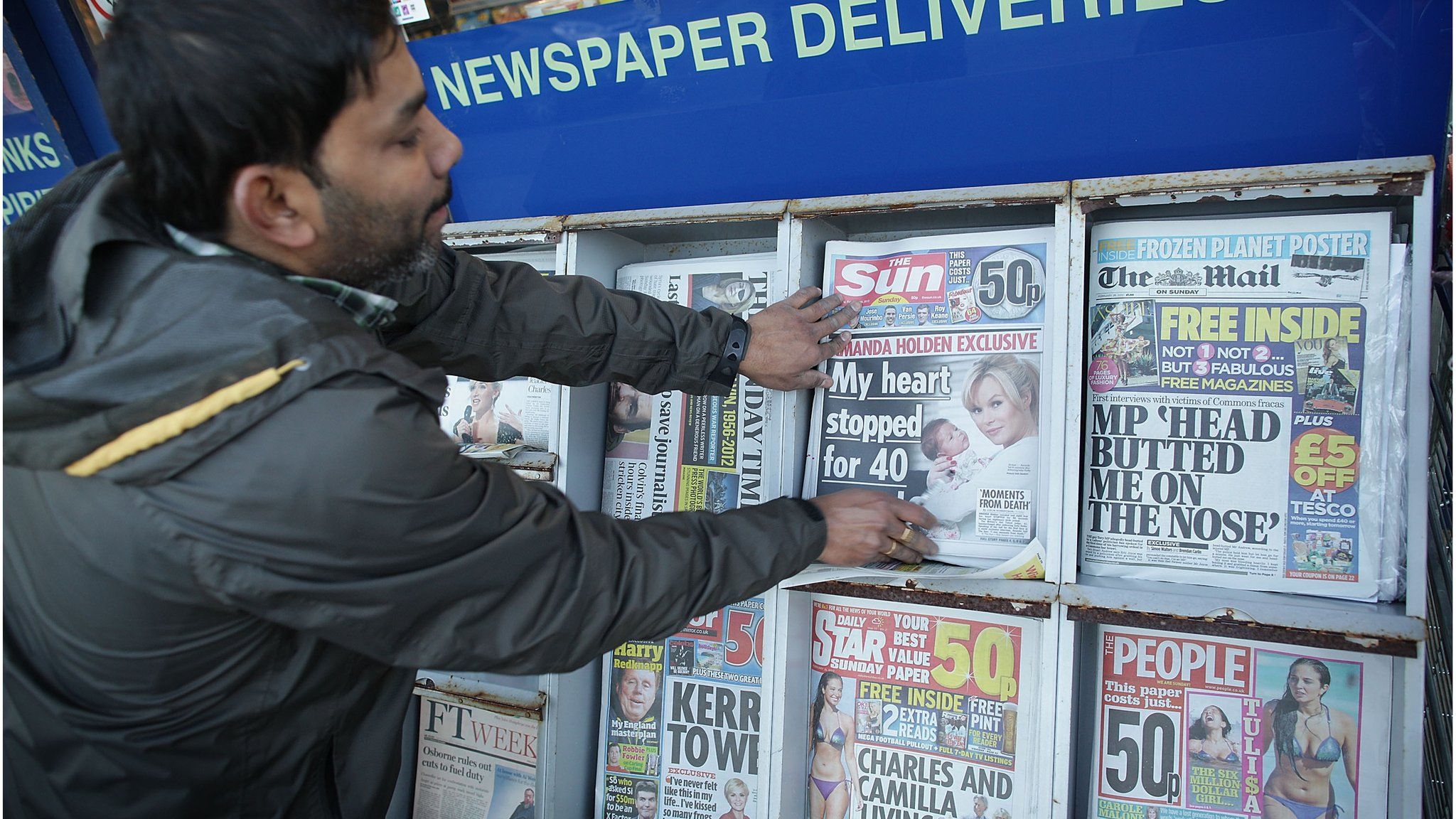 Man taking newspaper from stand