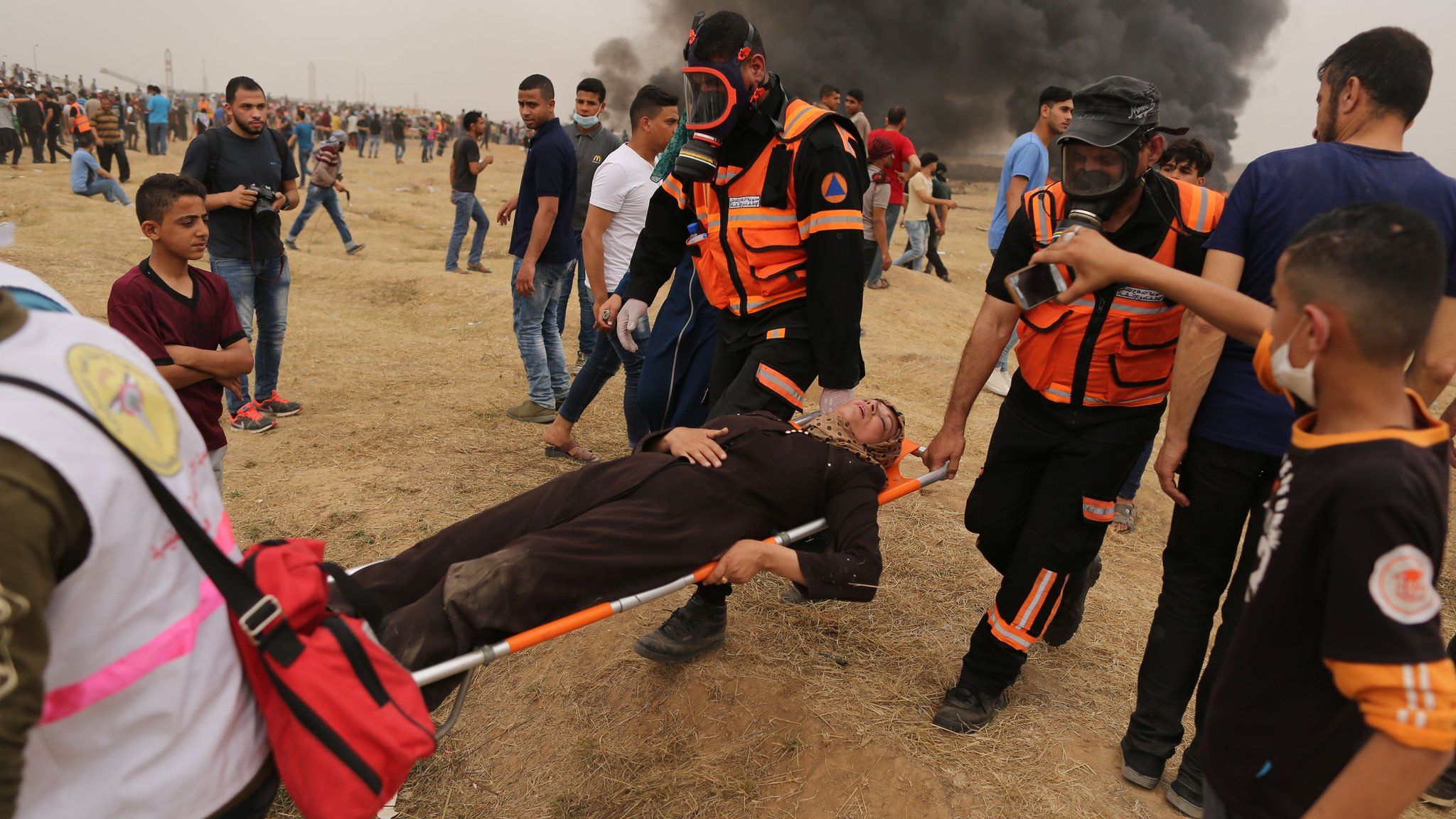 Palestinian medics carry an injured Palestinian woman during a protest near the Gaza-Israel border fence on 4 May 2018