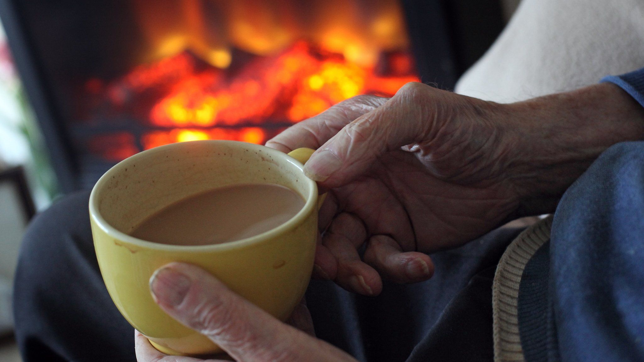 woman holds cup of tea by fire