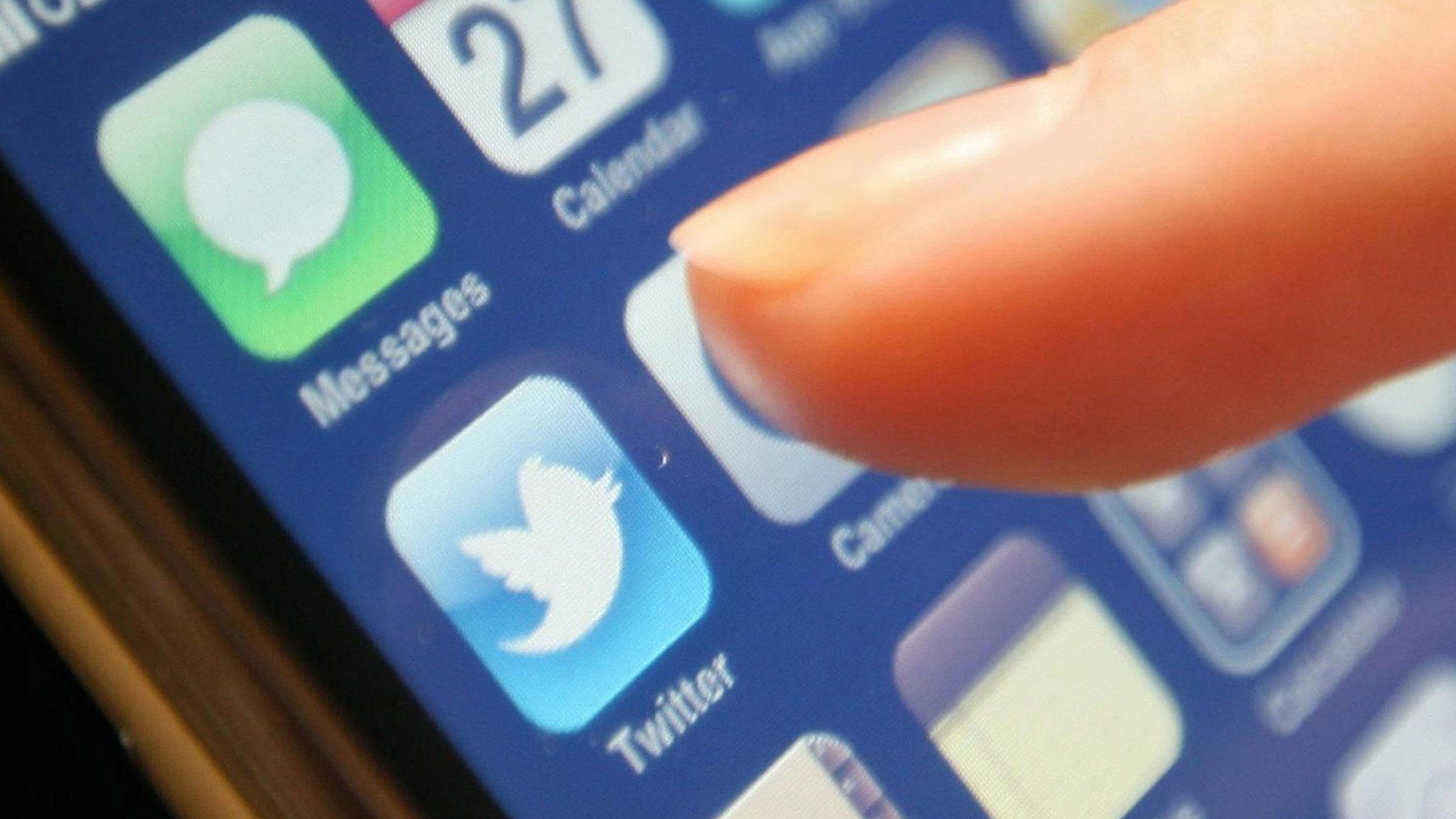 A finger about to press the Twitter button on a phone