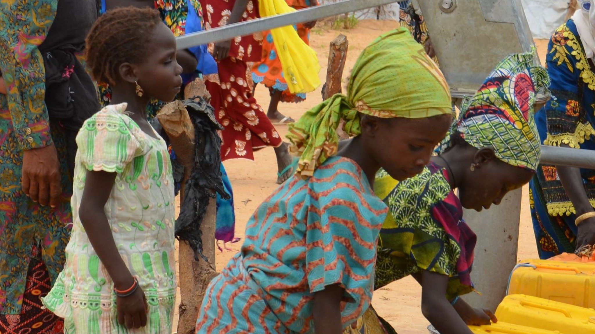 Displaced Nigerians who have fled Boko Haram fill water containers at a camp in Niger