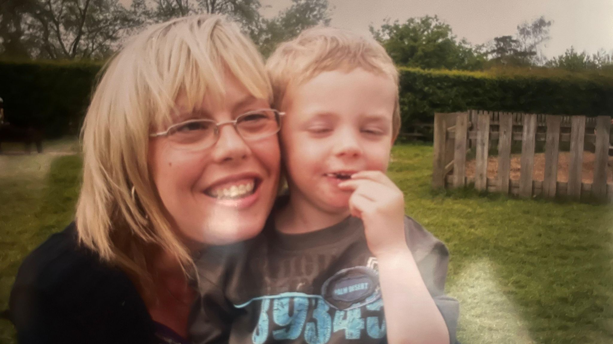 Karen Watts, who has shoulder-length fair hair and glasses, smiles as she cuddles her son, Alfie 