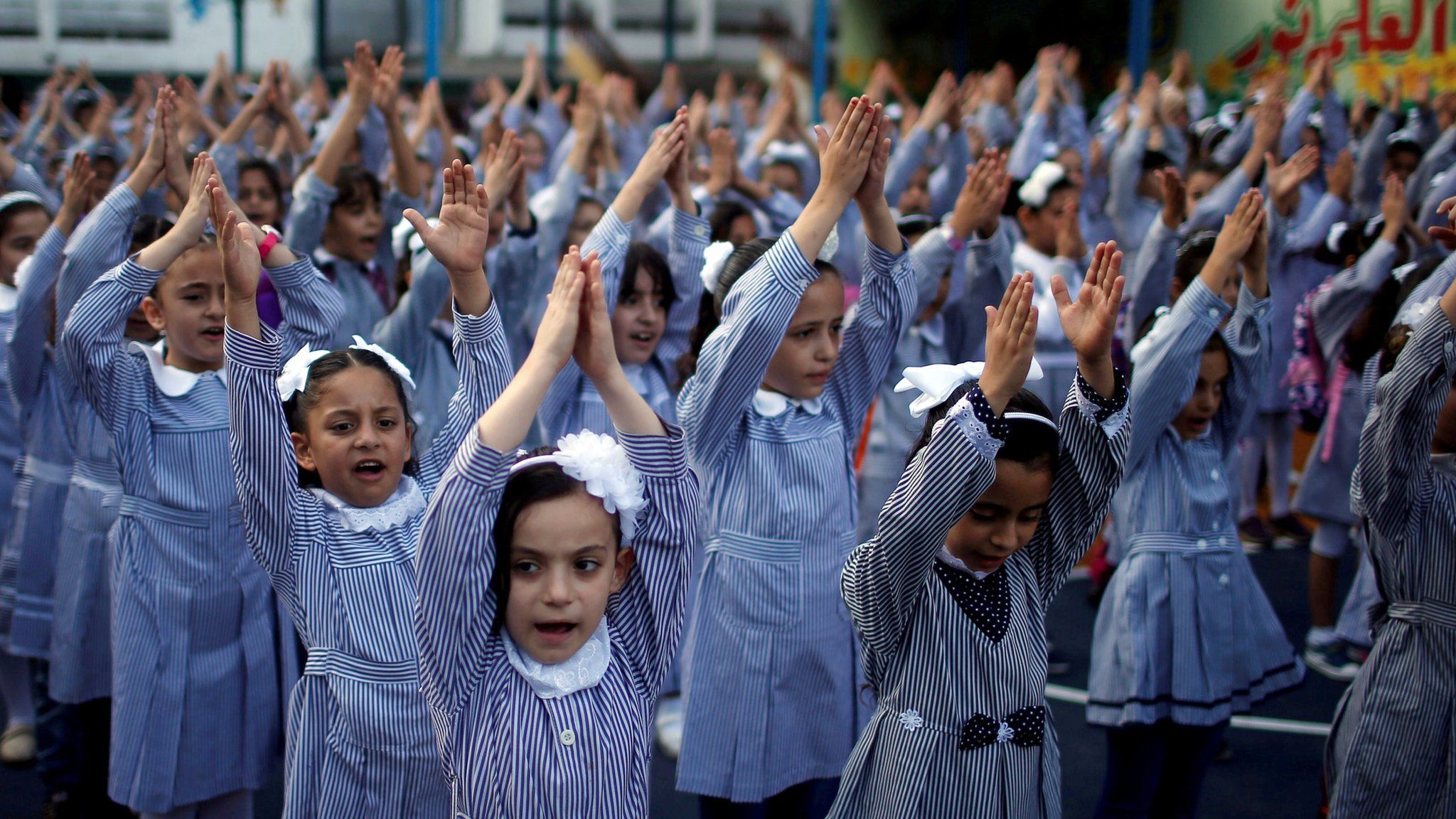 Palestinian school girls raise their hands during a morning exercise at a Unrwa-run school, in Gaza City, on 29 August 2018