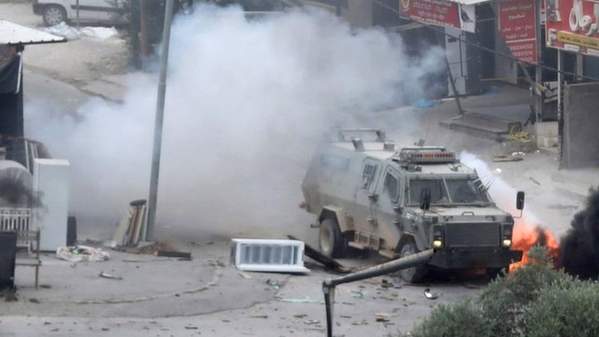 An explosive charge detonates near an Israeli armoured vehicle during an Israeli military raid in the West Bank city of Jenin (19 June 2023)