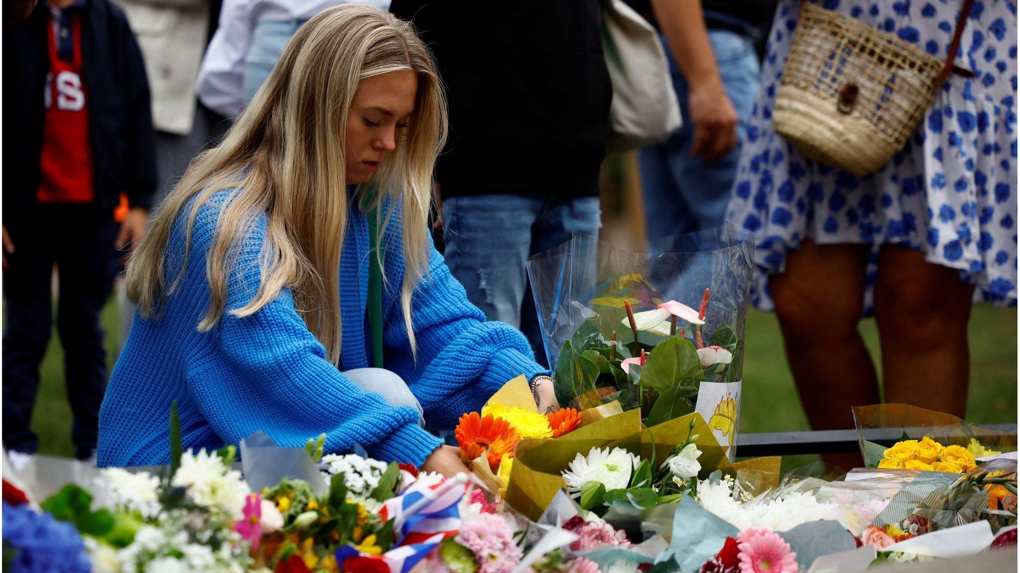 A woman places flowers in St. James' Park near Buckingham Palace (10 September 2022)