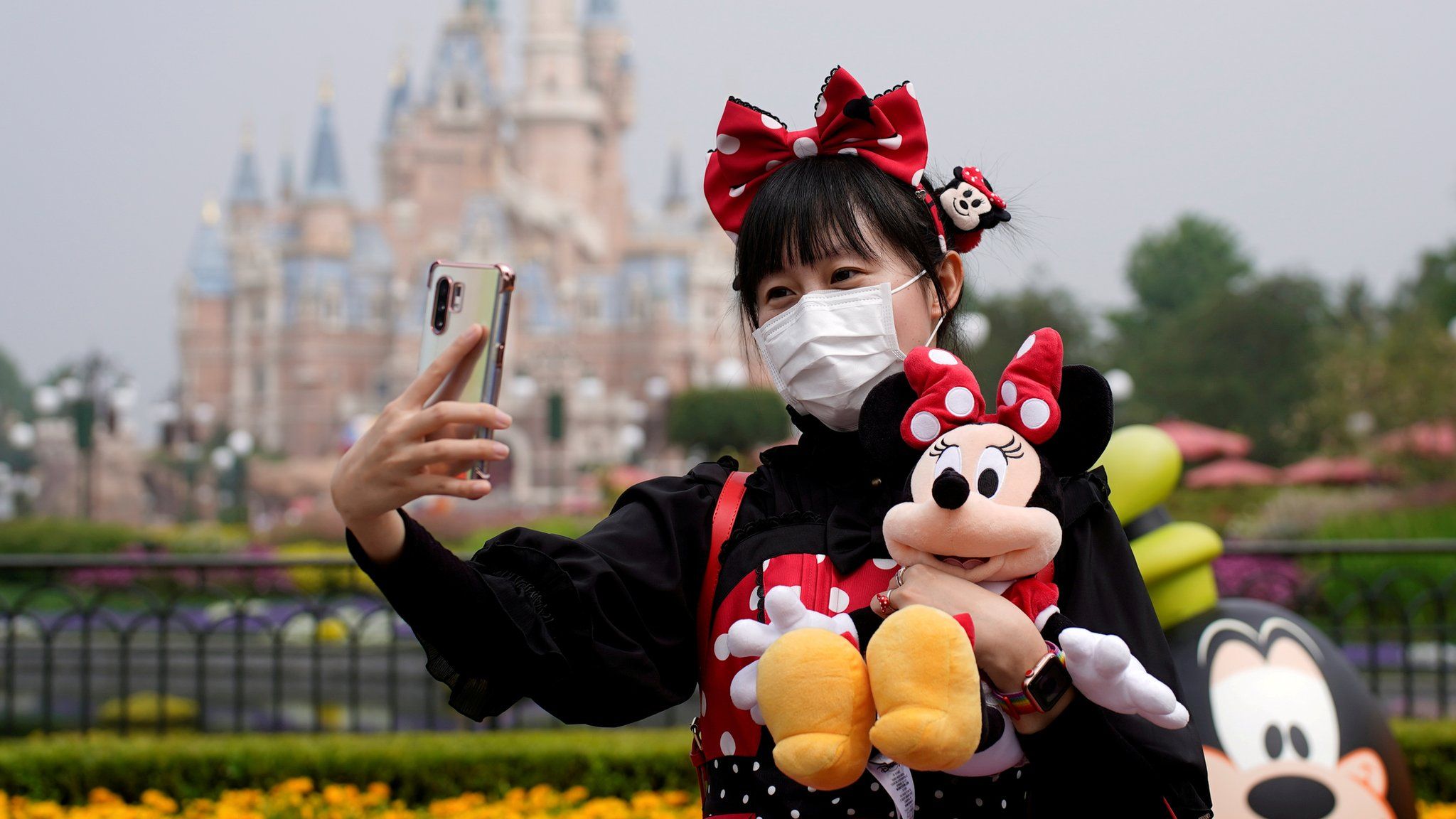 A visitor dressed as a Disney character takes a selfie while wearing a protective face mask at Shanghai Disney Resort as the Shanghai Disneyland theme park reopens following a shutdown due to the coronavirus disease (COVID-19) outbreak, in