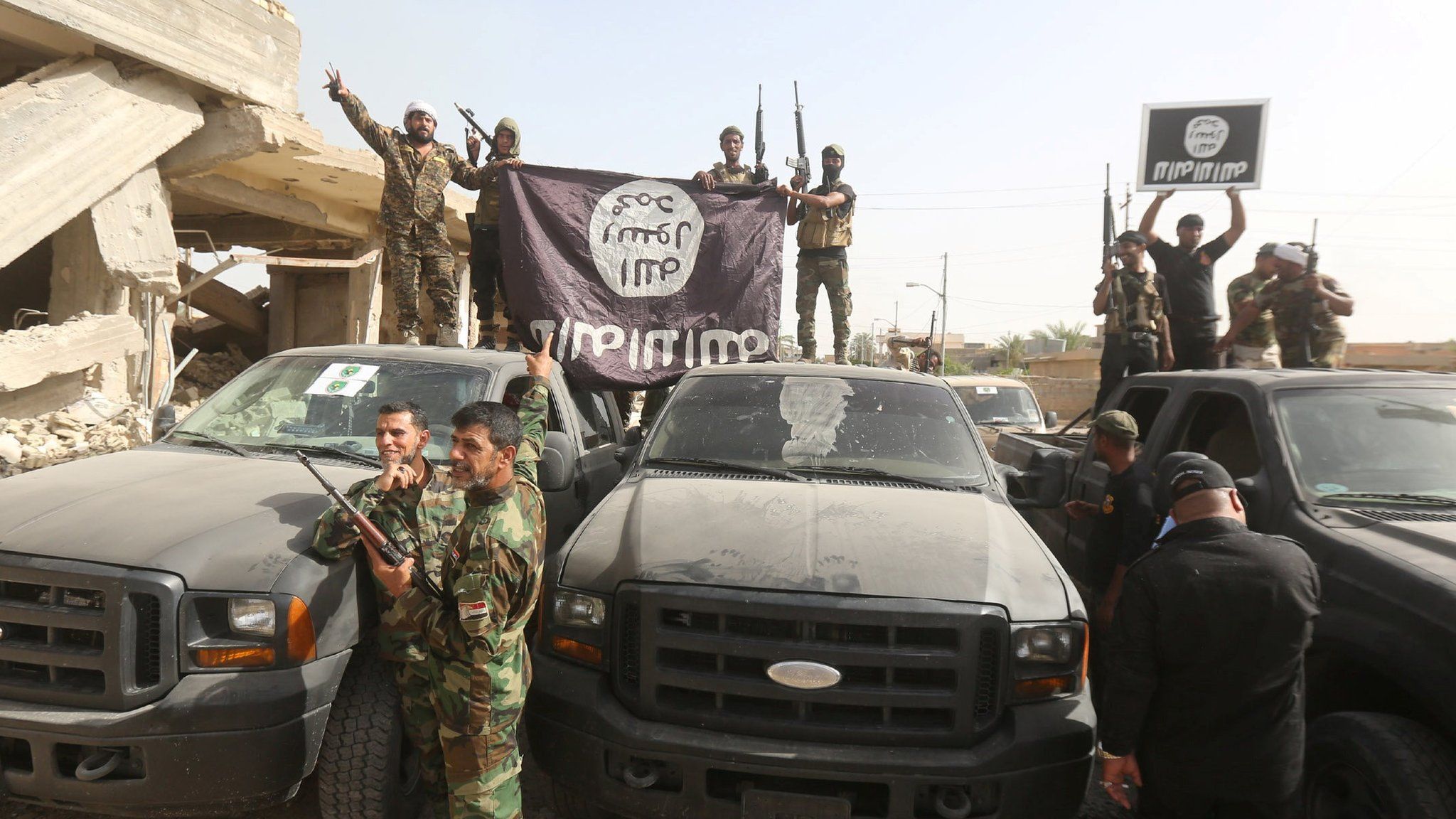 Shia militiamen hold an Islamic State group flag upside down after capturing Saqlawiya, outside Falluja (4 June 2016)