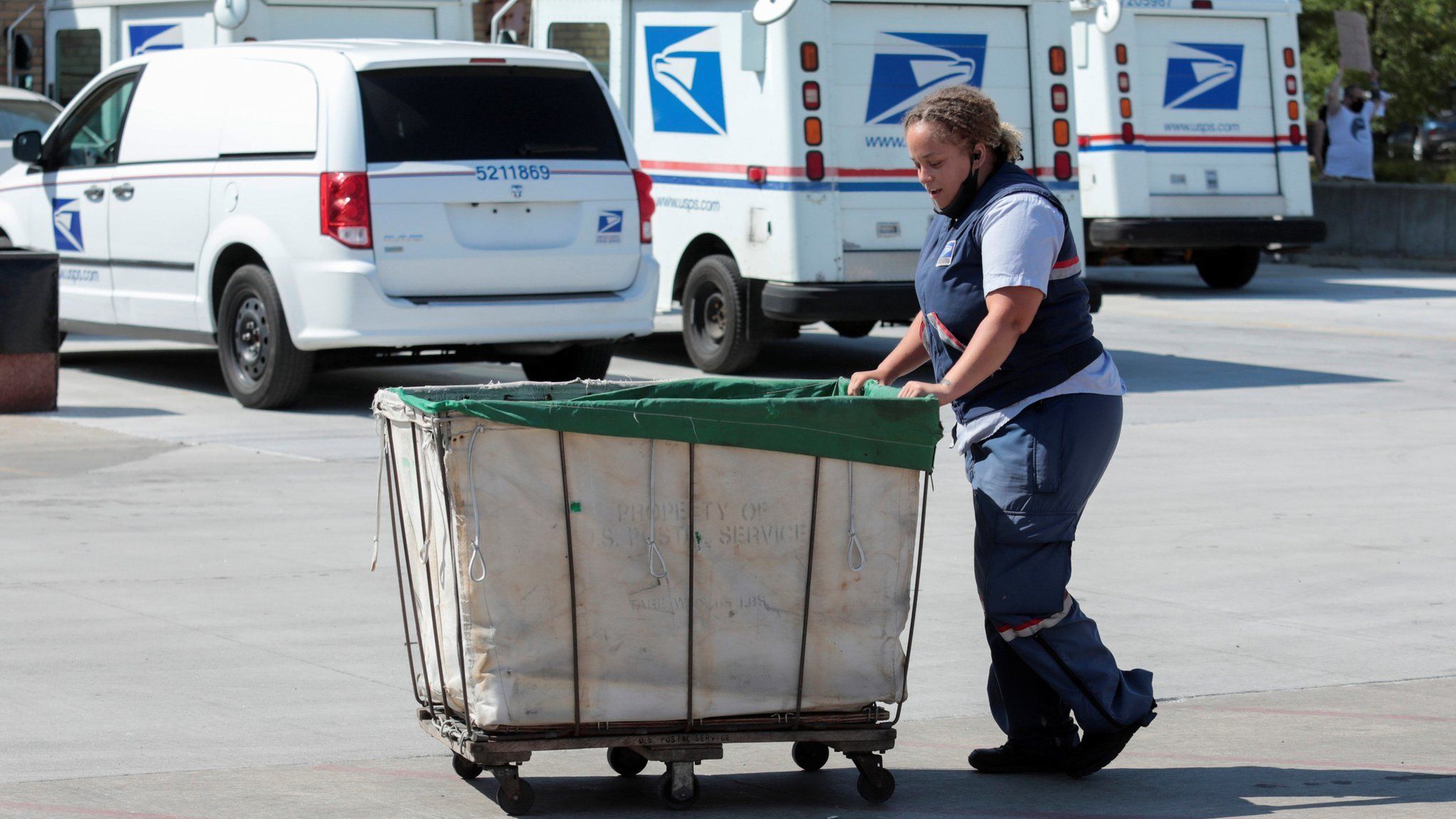 US Postal Service worker pushes a mail bin outside a post office in Royal Oak, Michigan (22 August 2020)