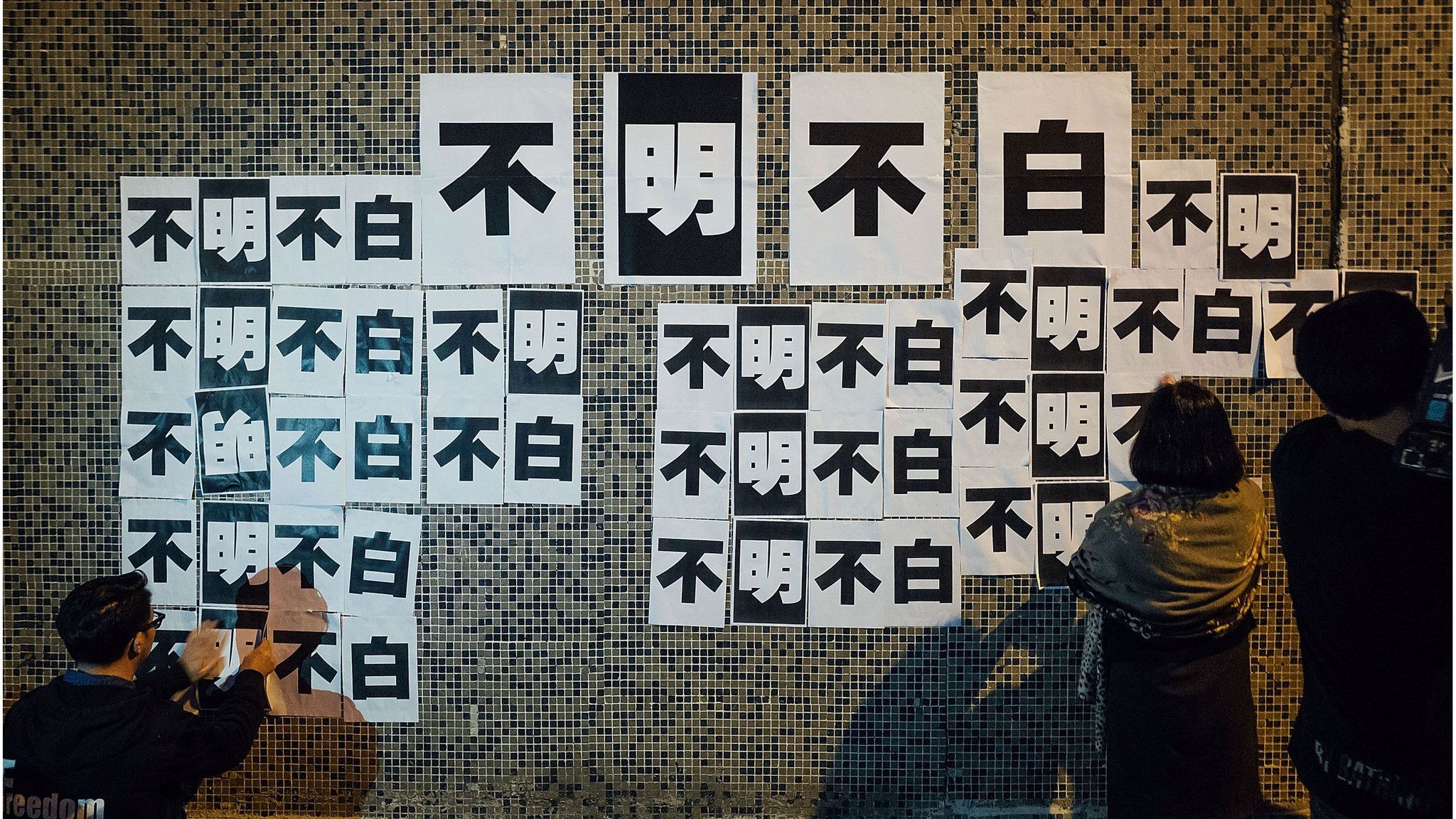 Staff members of Ming Pao put signs up on a wall saying "Unclear" in Chinese during a protest outside of Ming Pao headquarter on 20 April