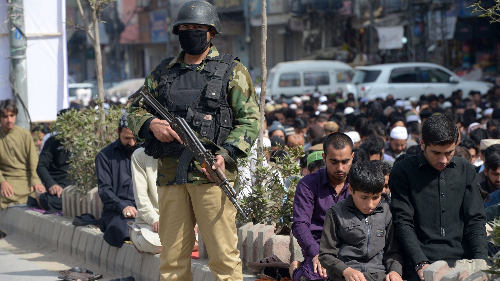 A Pakistani policeman stands guard as Muslim offer Friday prayers on a street in Peshawar on February 17, 2017, following bomb attack on a shrine of 13th century Muslim Sufi saint Lal Shahbaz Qalandar in the town of Sehwan in Sindh province, some 200 kilometres north-east of the provincial capital Karachi.