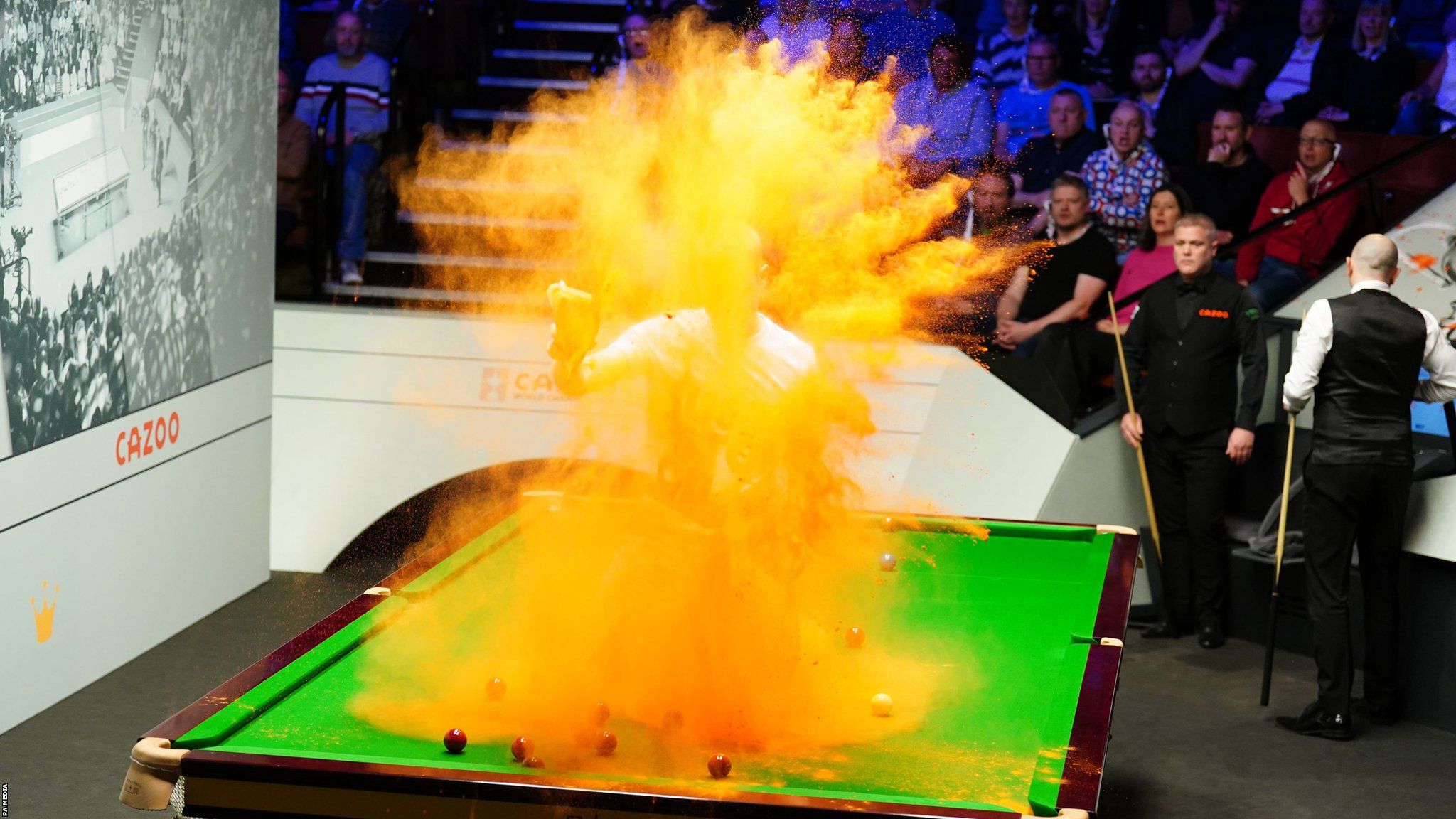 A protestor throws sand in the air while sat on table one at the snooker World Championship