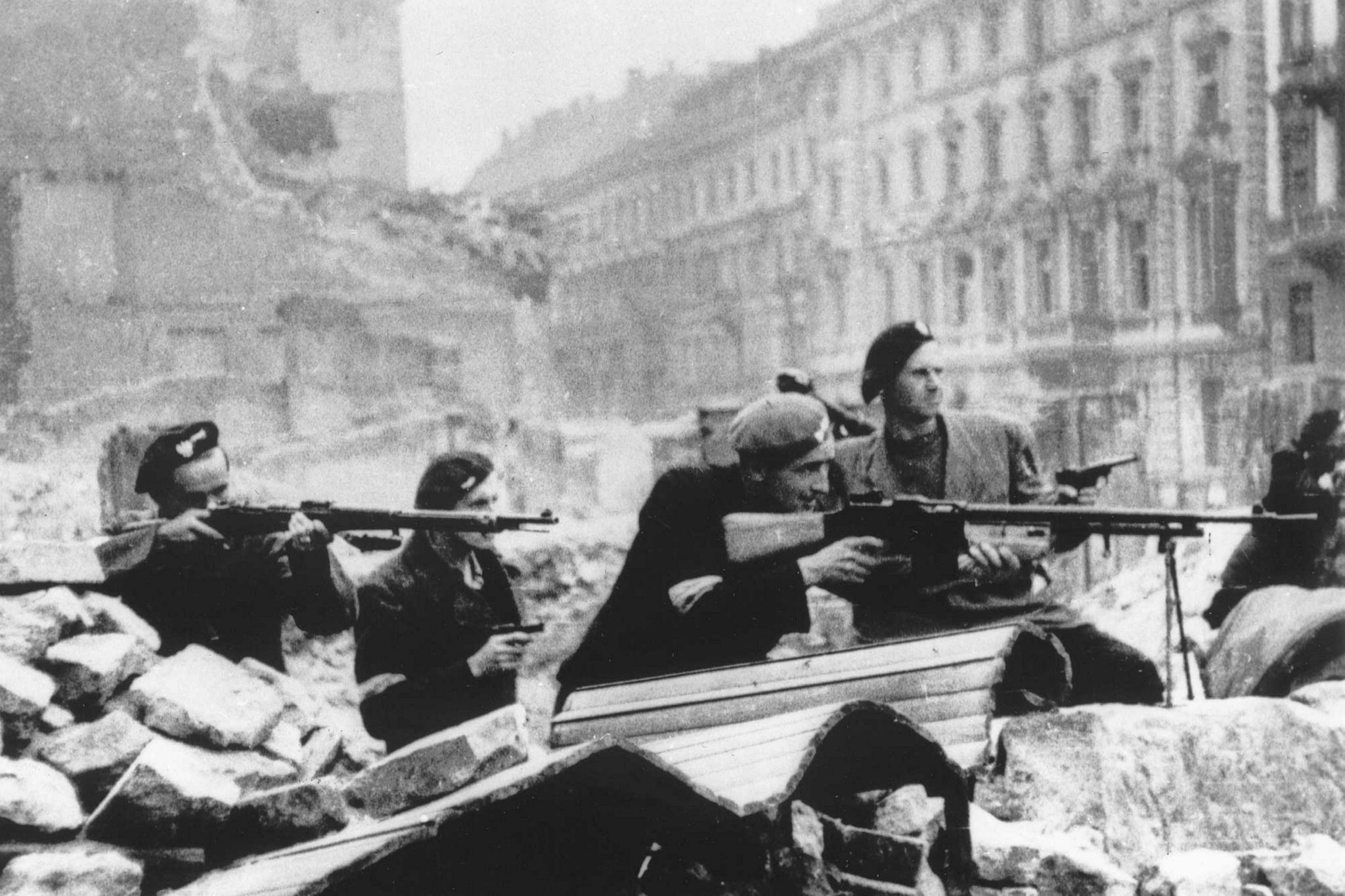 Black and white photo of Polish troops with guns surrounded by rubble in Warsaw