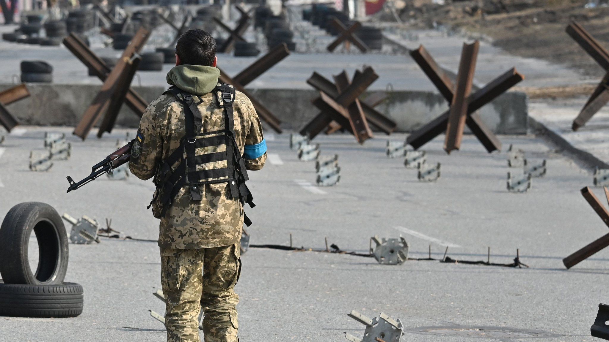 A Ukrainian soldier passes by anti-tank protection elements as he stands guard at a checkpoint in the outskirt of Kyiv on March 28, 2022. (