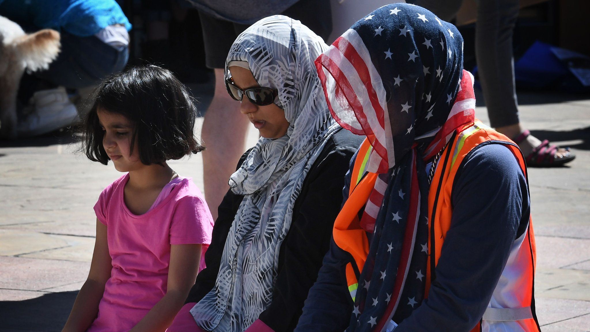 Muslim women pray before participating in the "#NoMuslimBanEver" rally in downtown Los Angeles