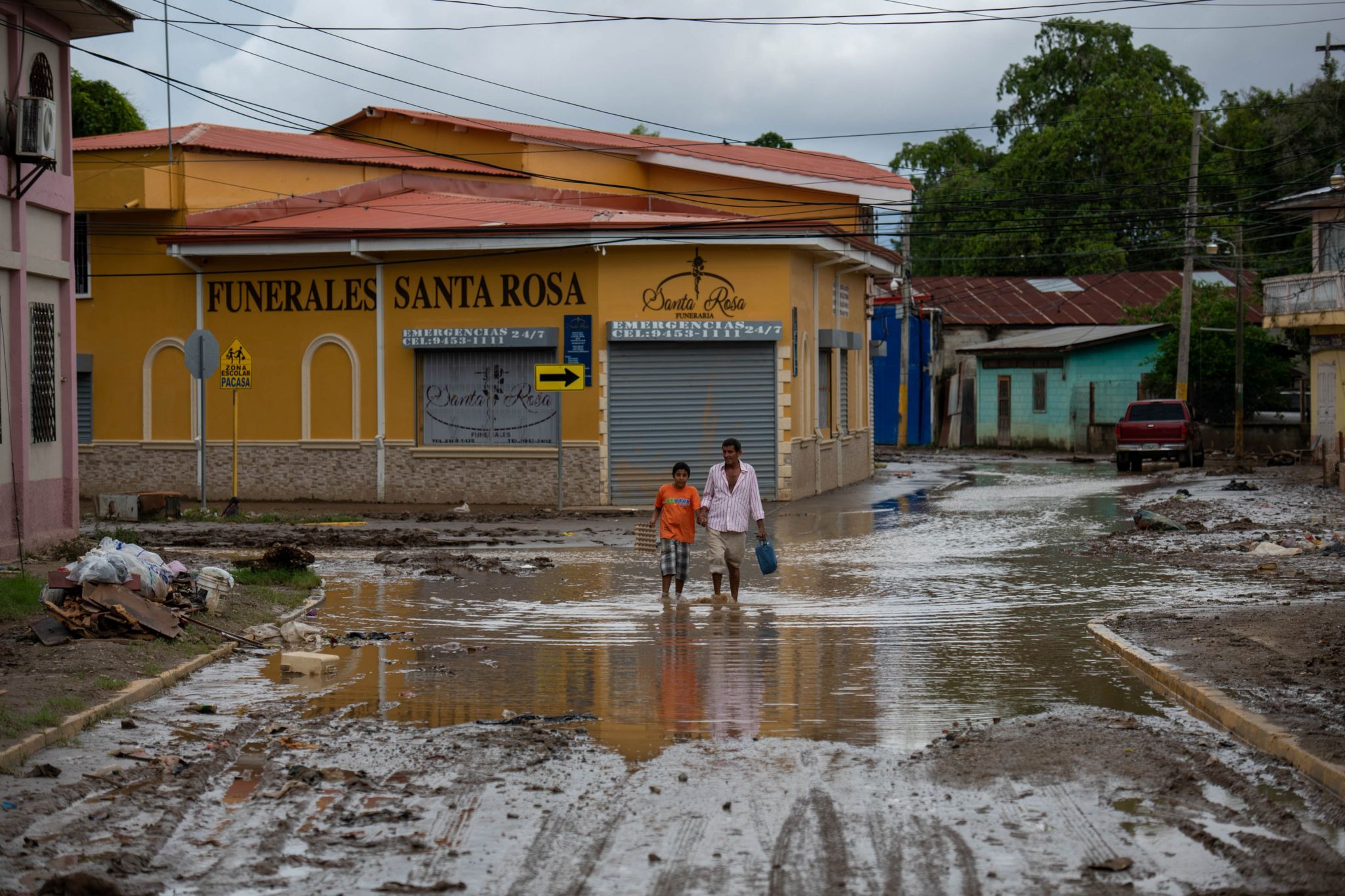 A view of two people walking along a muddy street in Valle de de Sula
