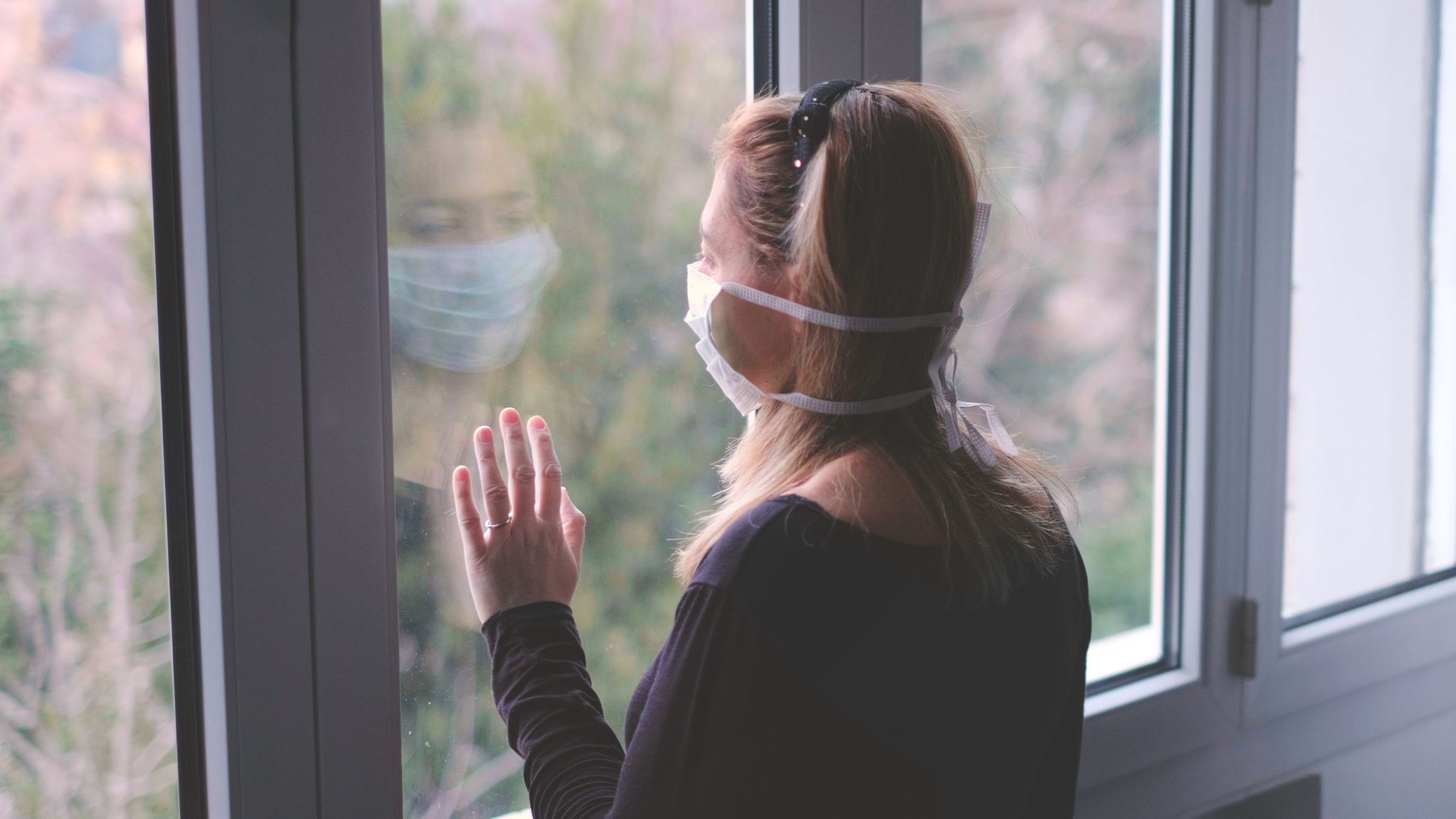 woman in mask looking out window