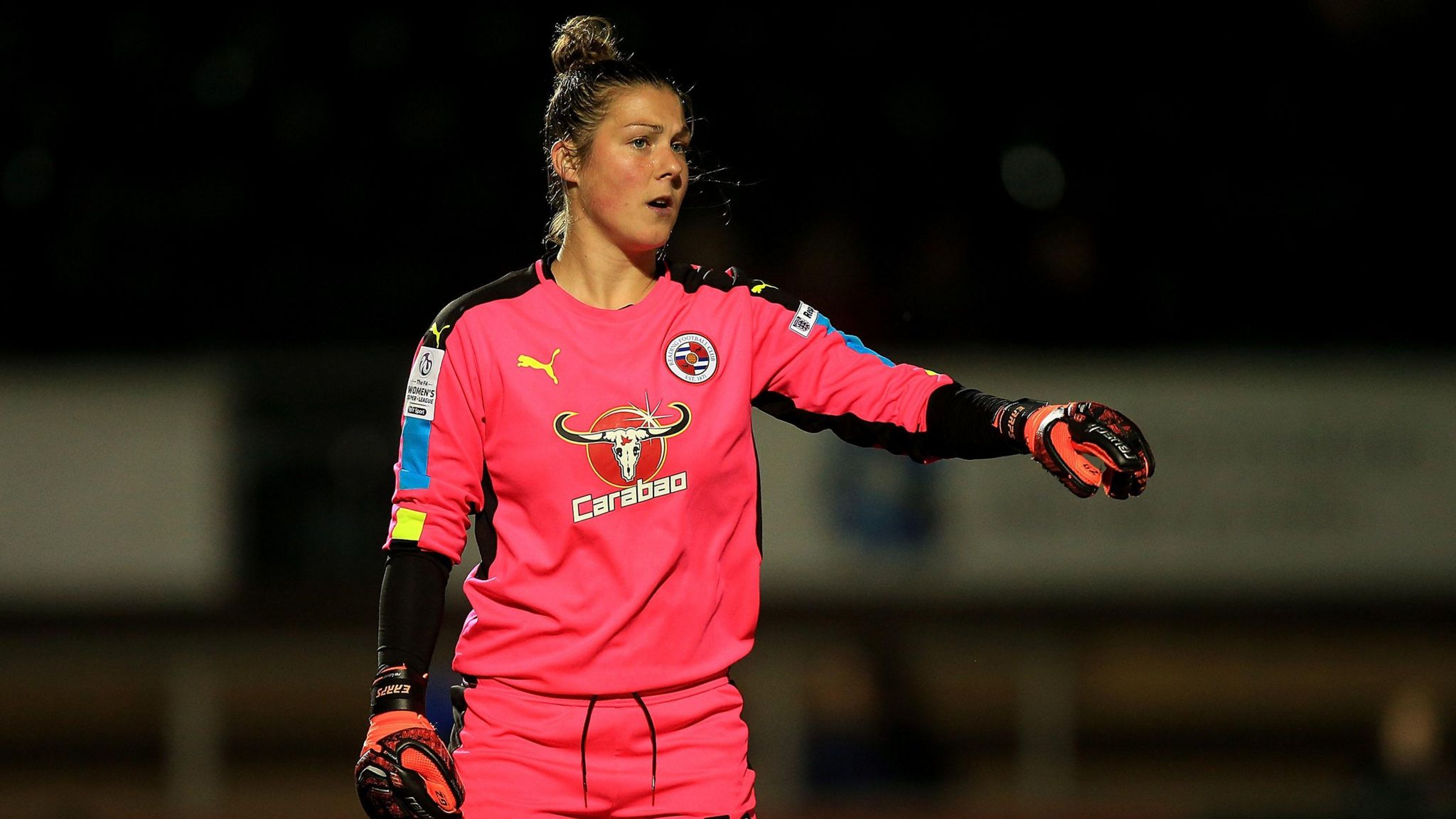 Mary Earps wearing a bright pink Reading goalkeeper's shirt points during a match