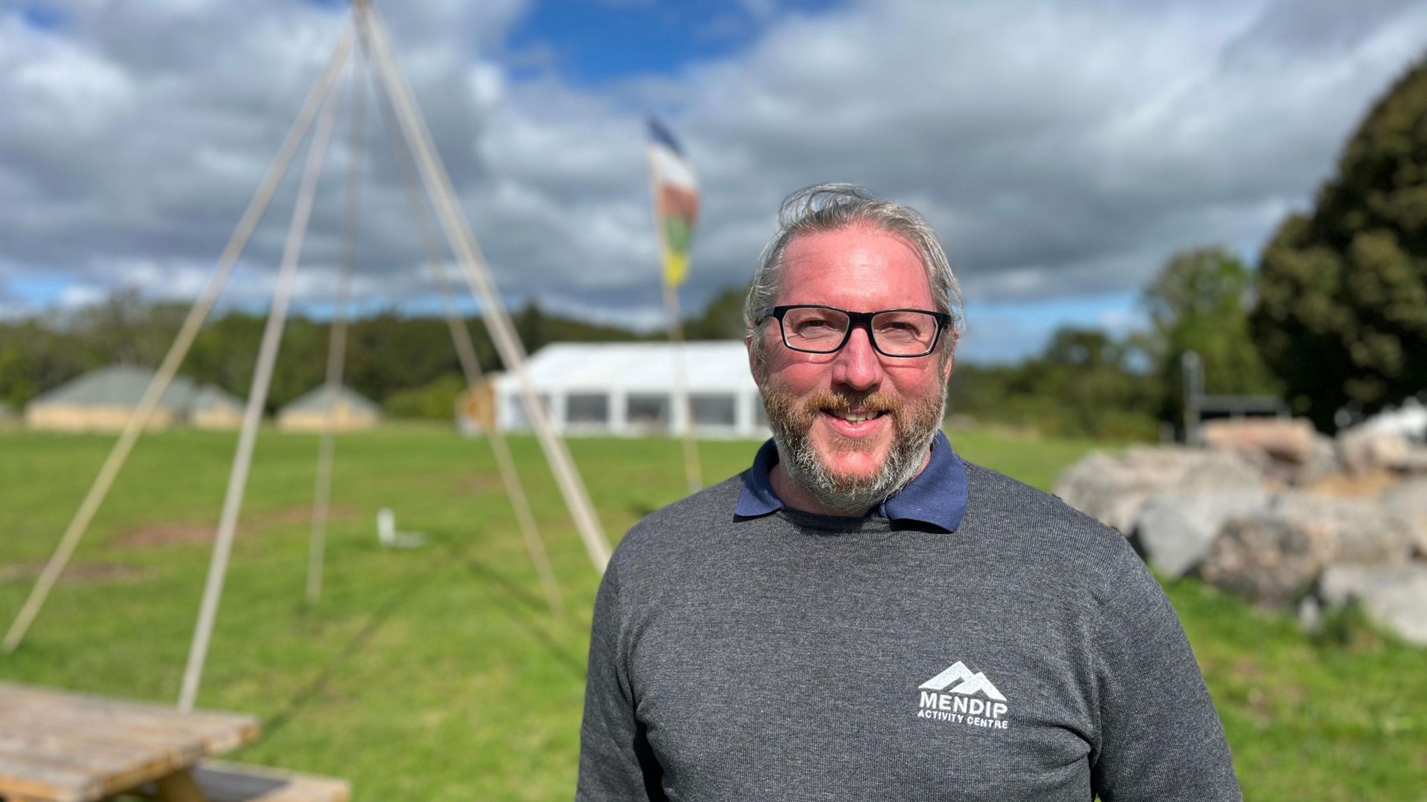 David Eddins in a grey sweater standing at the activity centre in front of a tipi