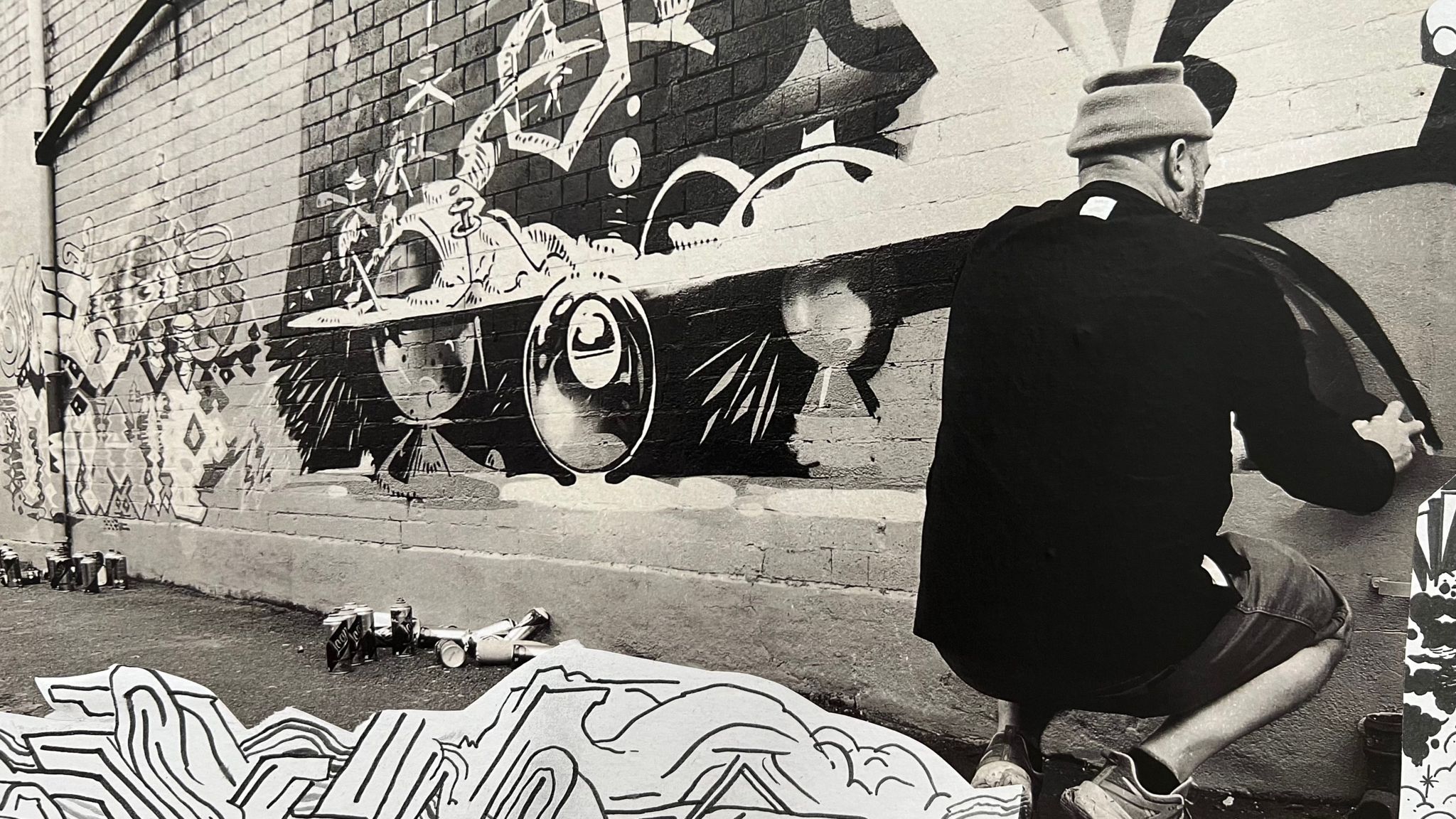 Black and white image of a man spraying paint onto a wall