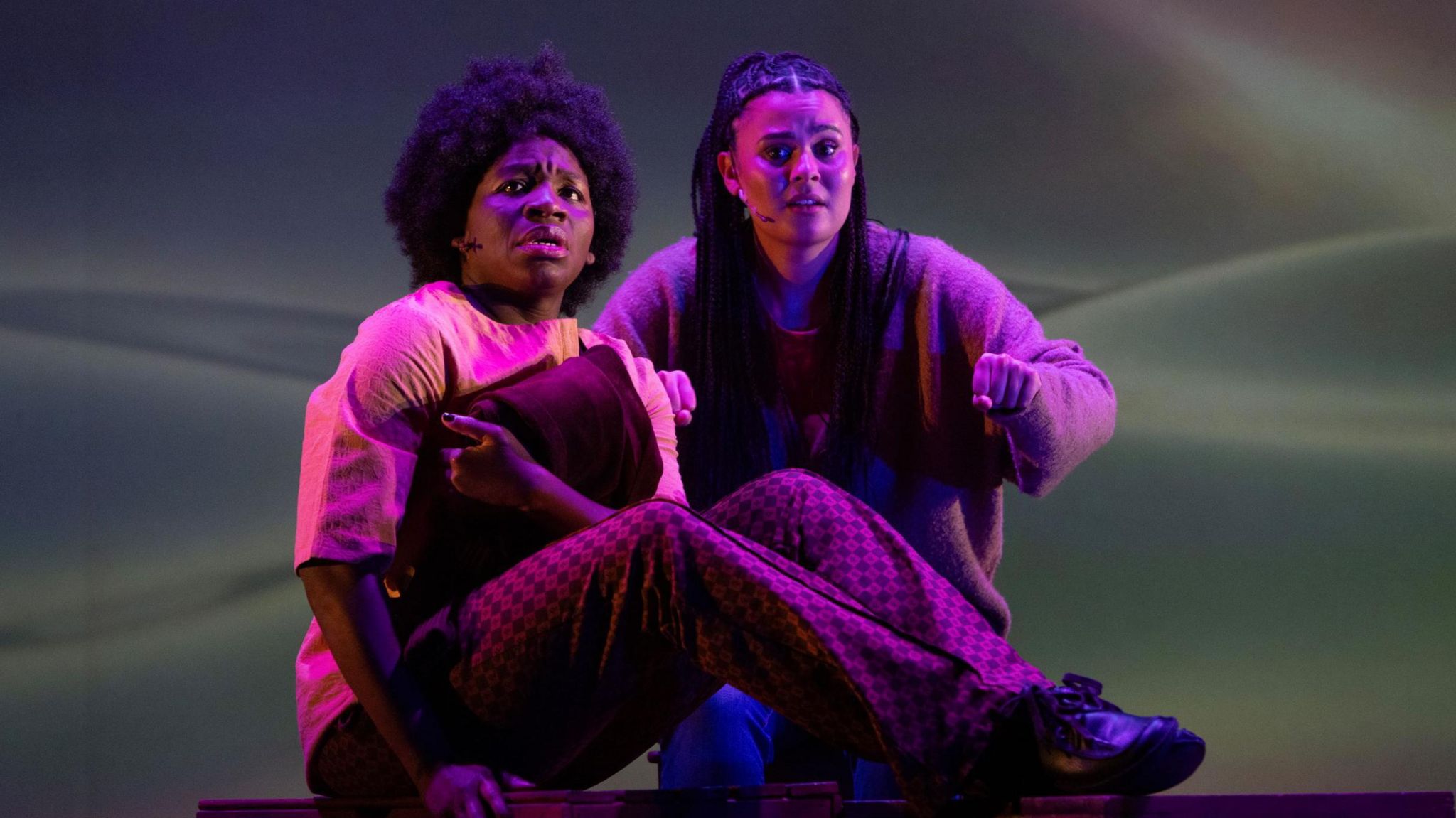 Apphia Campbell and a fellow actor on stage in purple lighting