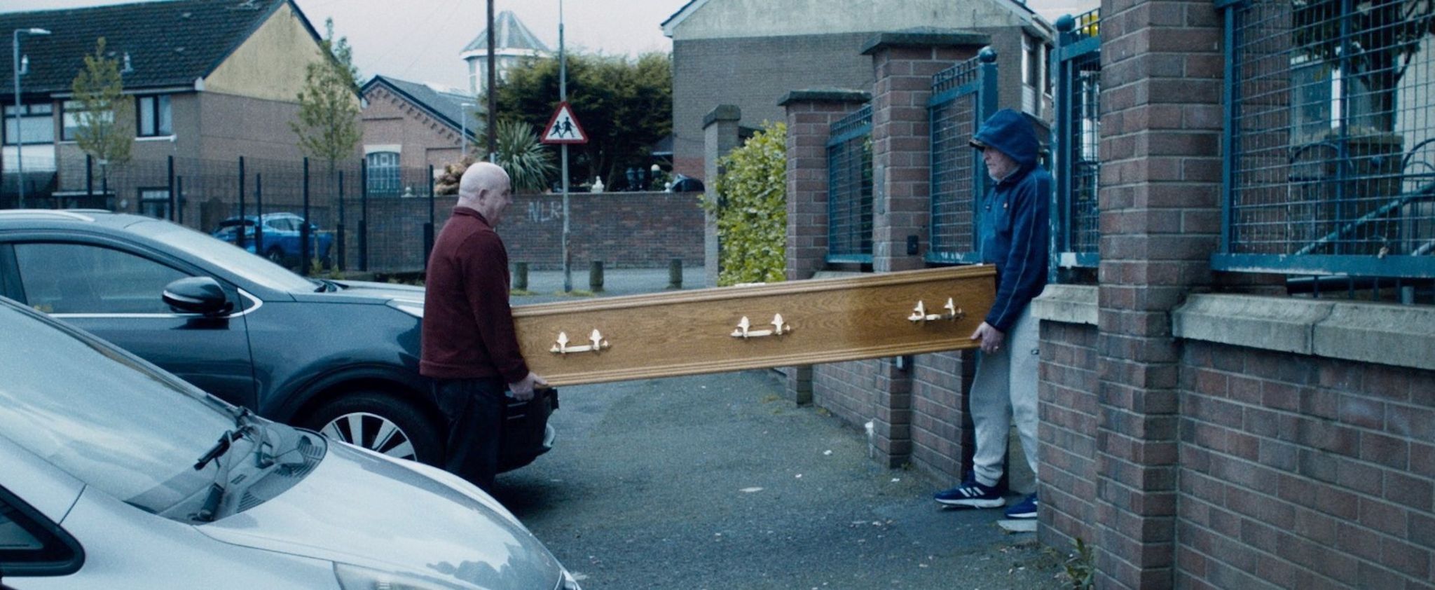 The flats - two men carrying coffin into New Lodge estate