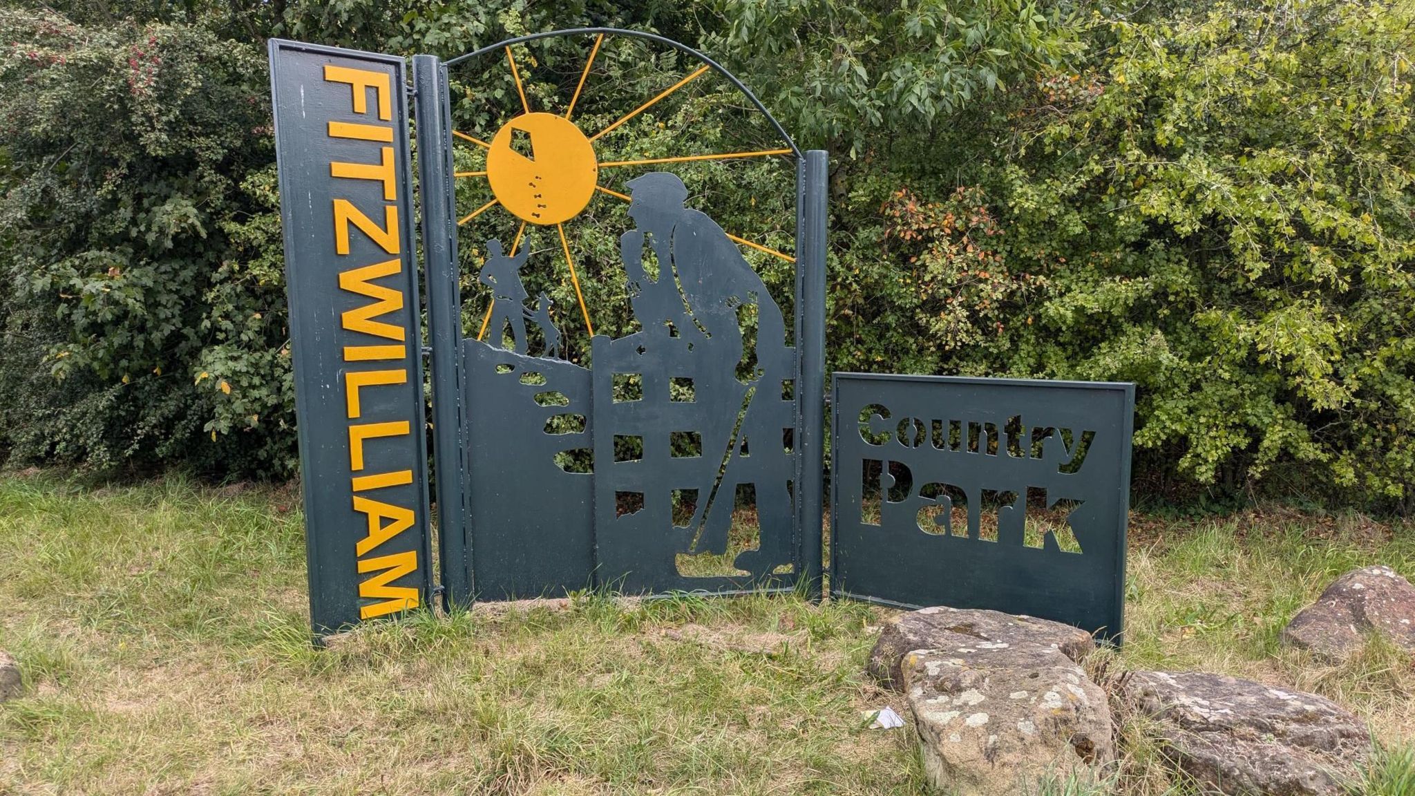 A sign indicating the entrance to Fitzwilliam Country Park, which features a 2D sculpture of miners at work