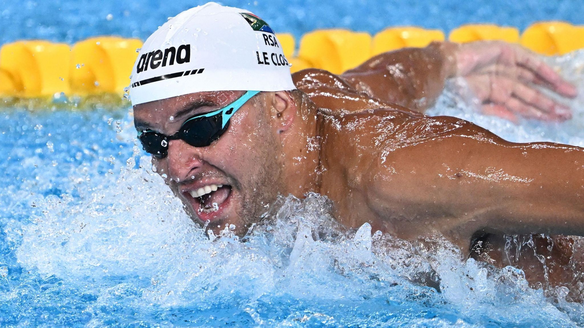 Chad le Clos, wearing black and blue goggles and a white swim cap, pictured during a butterfly race