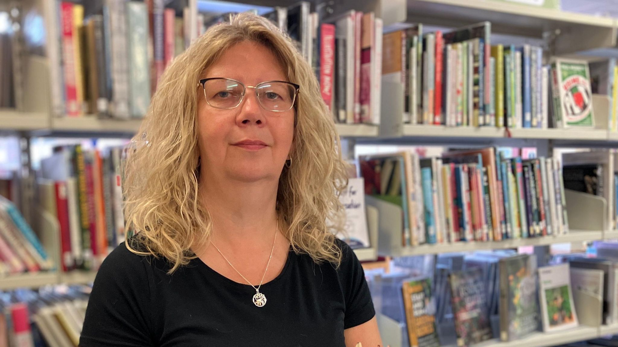 Town manager standing in front of the garden and crafts shelves at Newport library in Shropshire