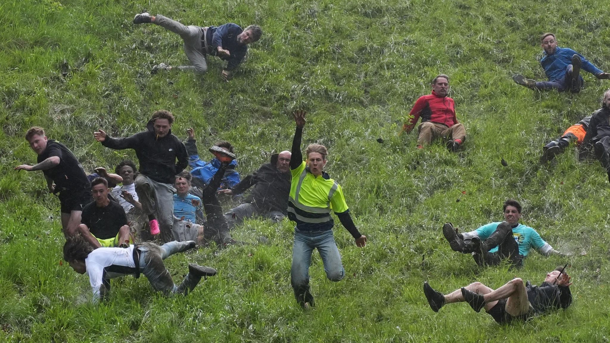 Men tumbling down the hill with the winner still standing and holding his hand in the air