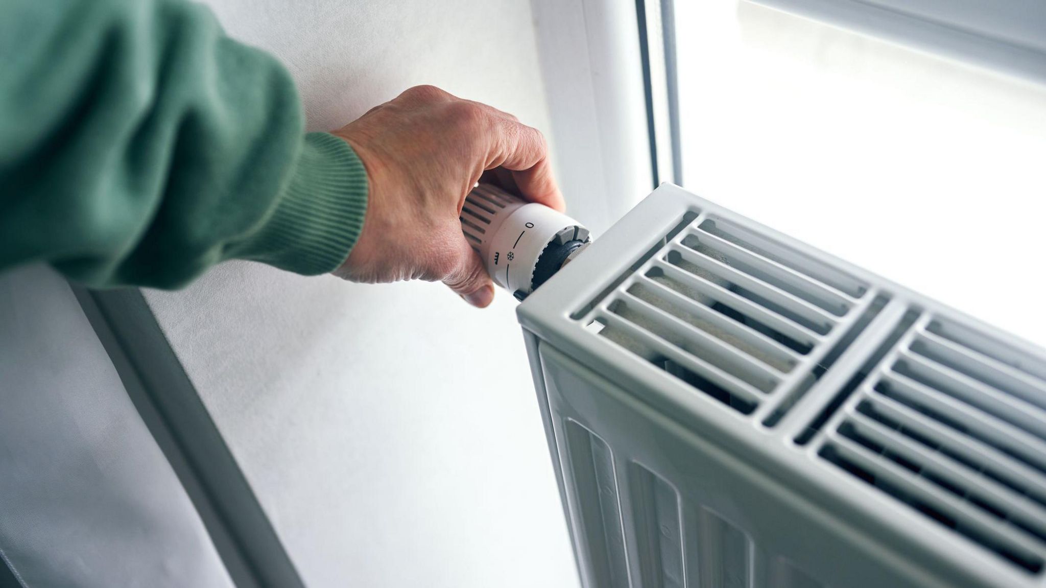 A hand turning a knob on a radiator 