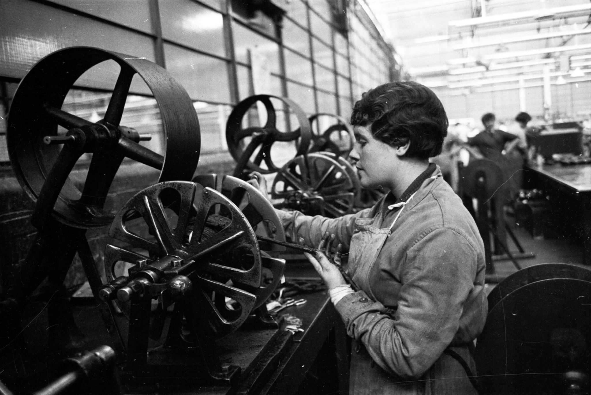 20th August 1955: A woman working the industrial machinery at a Glasgow factory. Glasgow is responsible for more than half of Scotland's industrial output and there are many factories on the Clydeside industrial estates including the Olivetti plant at Queenslie. There are also shipbuilding yards, locomotive production plants and factories owned by tobacco and biscuit companies. Original Publication: Picture Post - 7942 - Let Glasgow Flourish! - pub. 1955 (Photo by Haywood Magee/Picture Post/Hulton Archive/Getty Images)