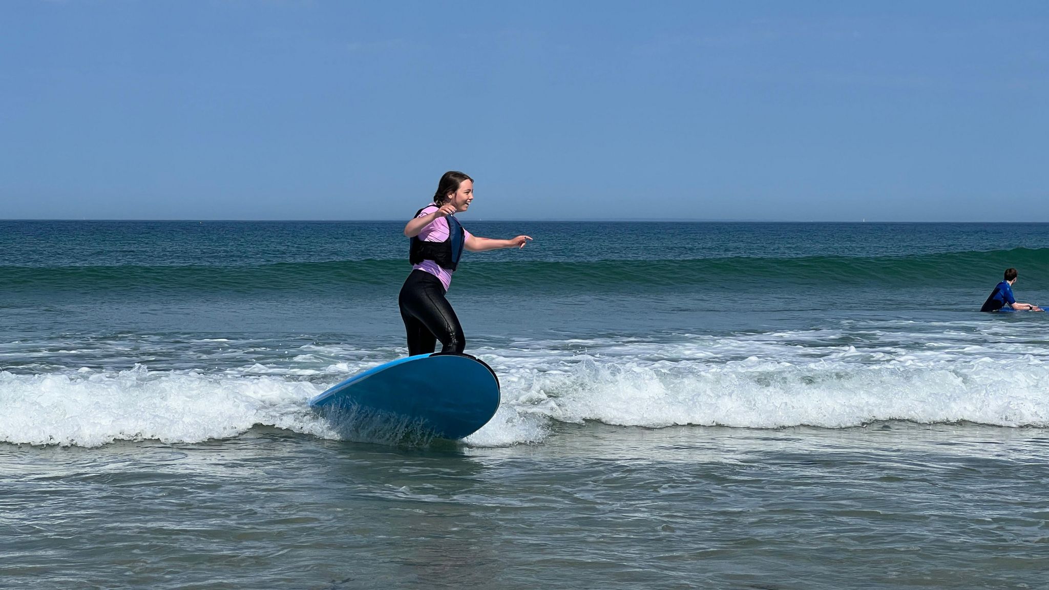 A young girl smiles as she surfs on a small wave