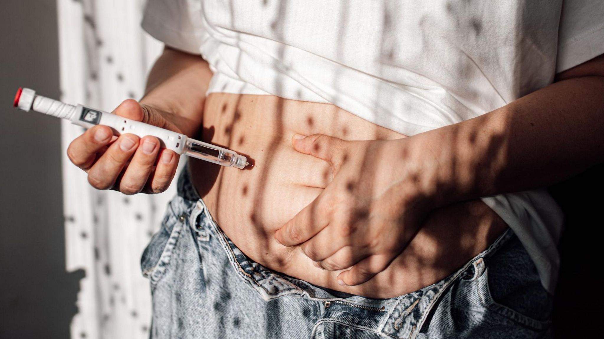 Someone injecting a weight-loss drug into their stomach