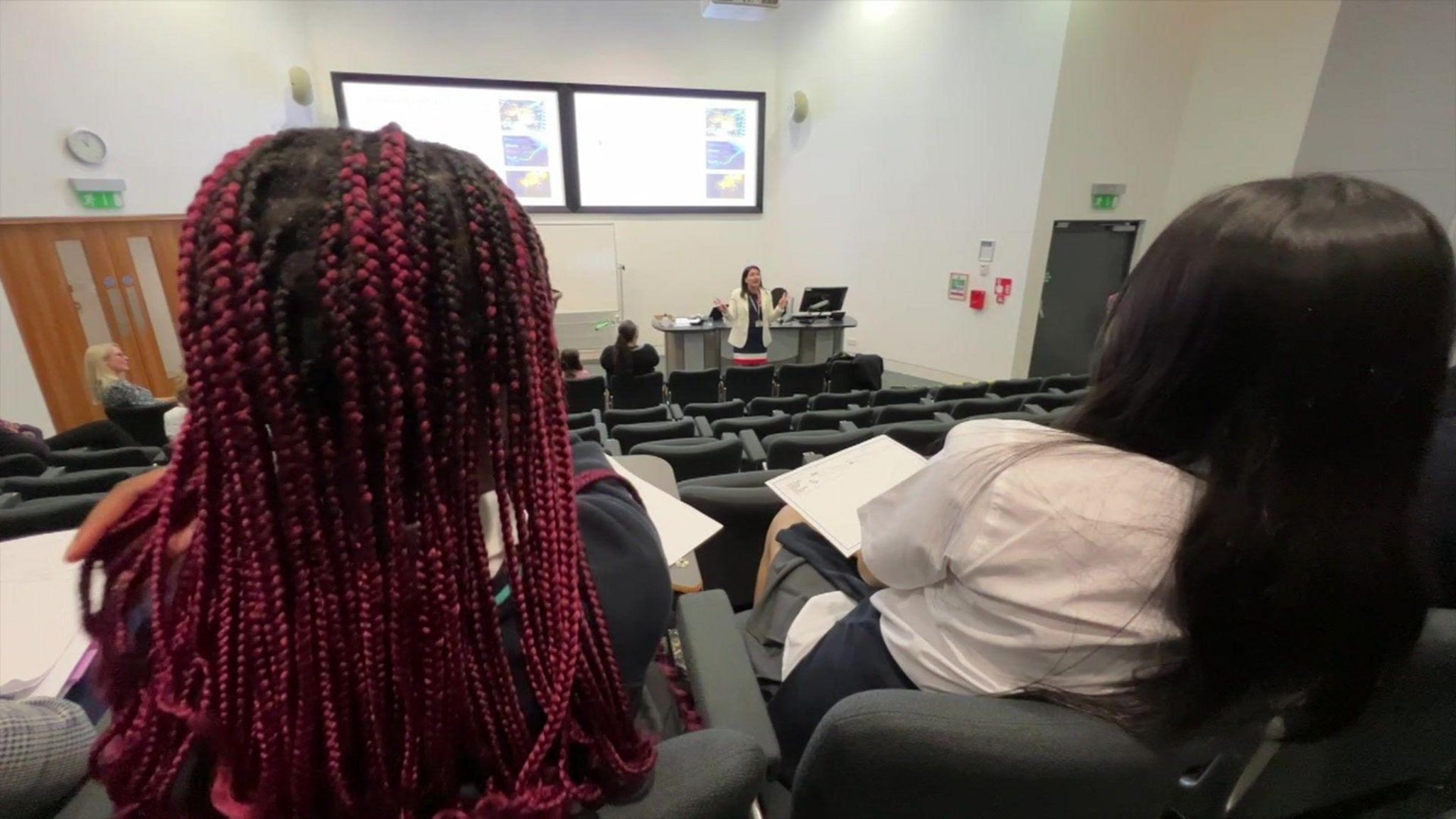 Back of heads of two female students watching a lecture