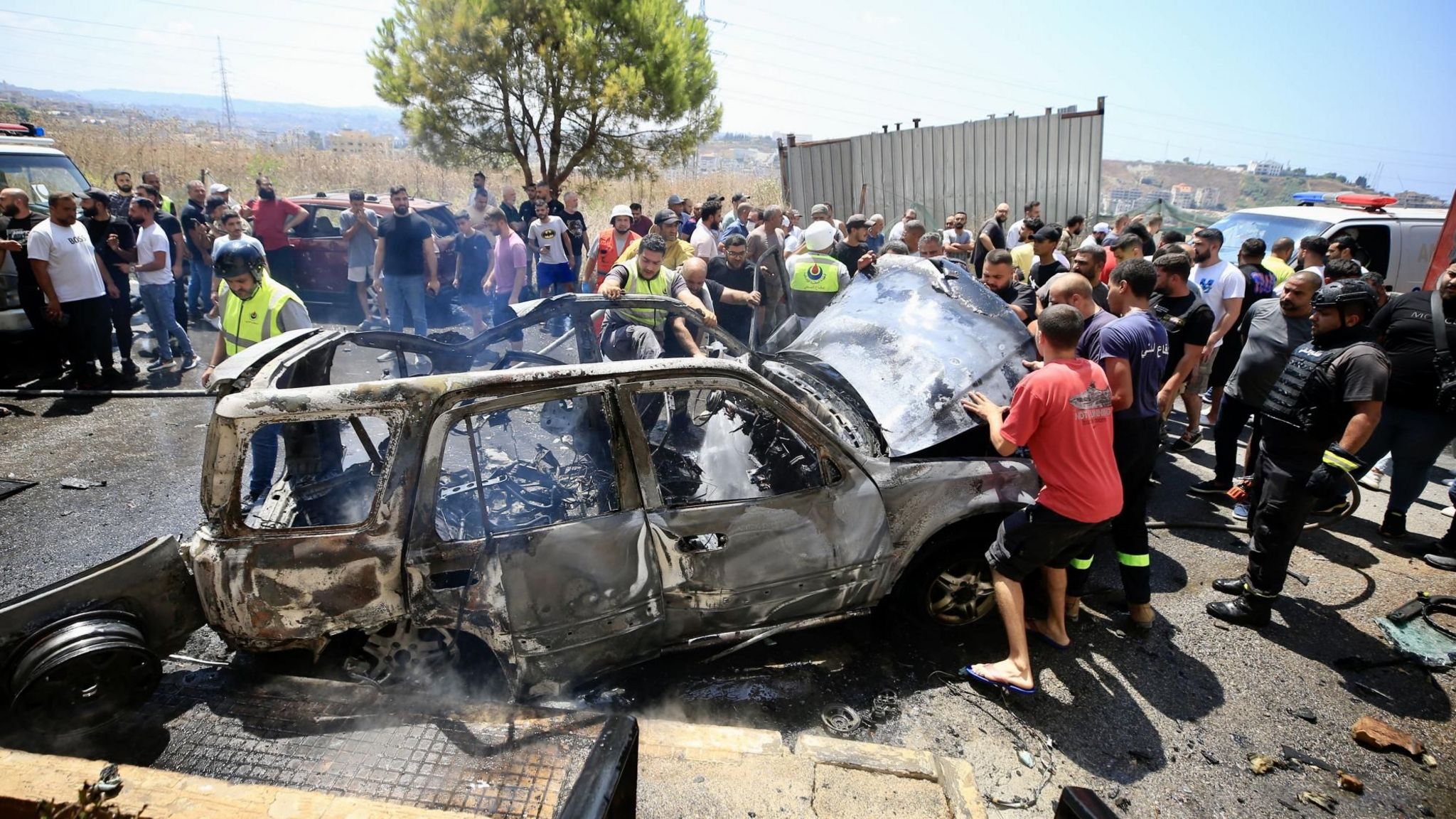 Lebanese rescue workers inspect a vehicle destroyed in a reported Israeli drone strike in Sidon, southern Lebanon (26 August 2024)