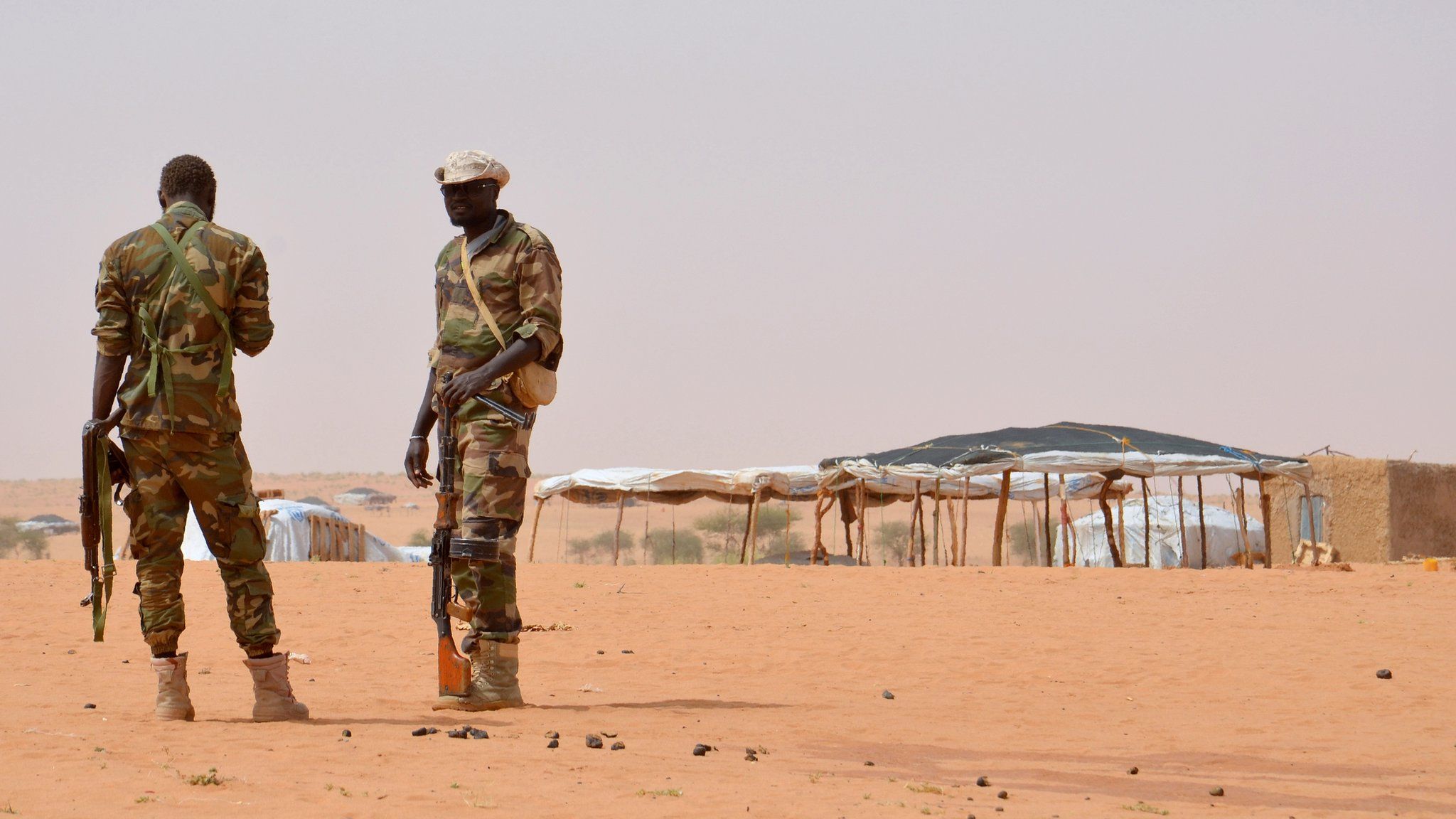 Niger soldiers stand guard during a visit by the Interior Minister Mohamed Bazoum on October 21, 2016 to the in Tazalit United Nations refugee camp in the Tahoua region some 300 kilometres northeast of the capital Niamey, where 22 soldiers were killed on October 7 by Islamic militants.