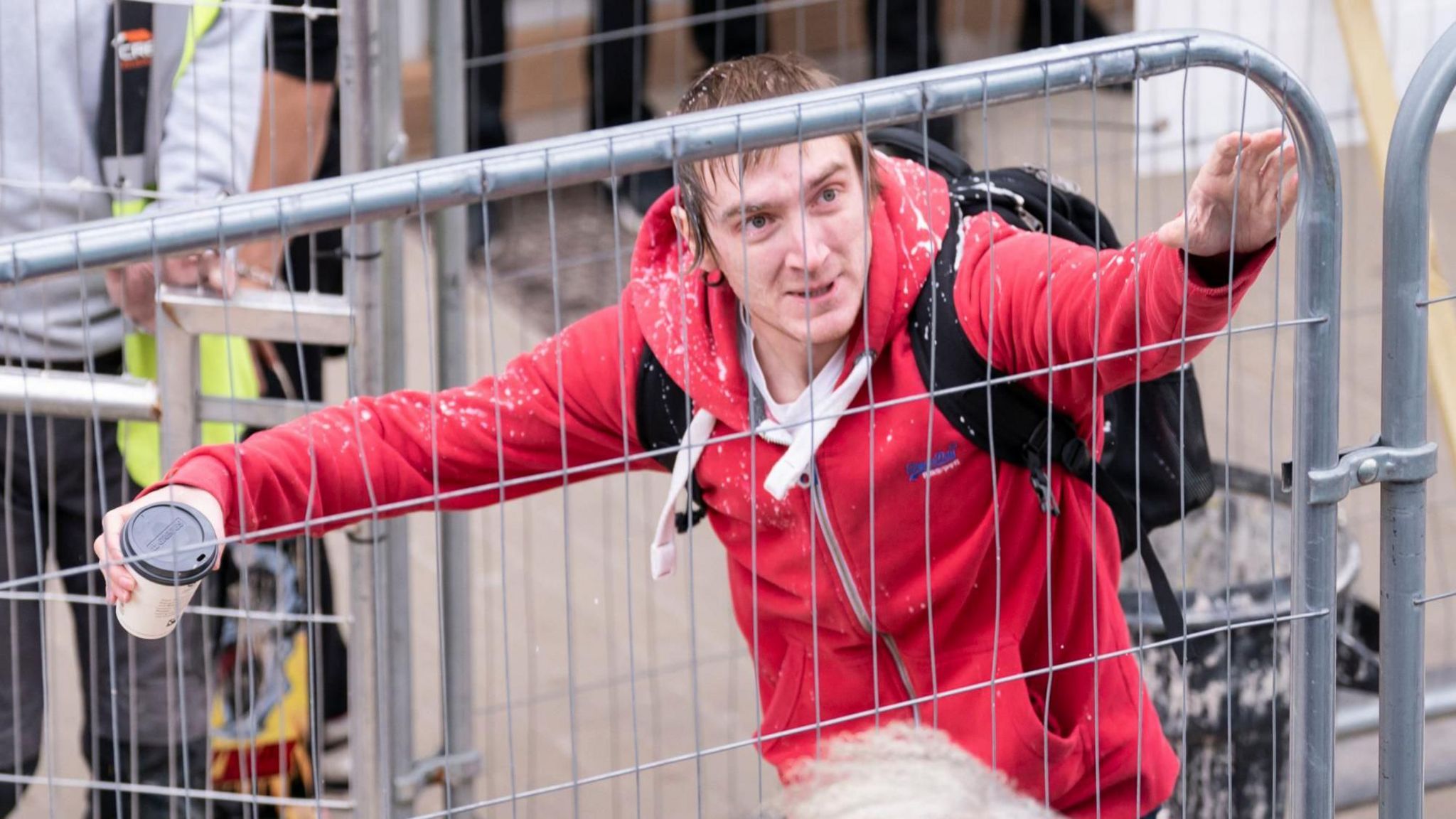 A man in a red jacket holding a cup