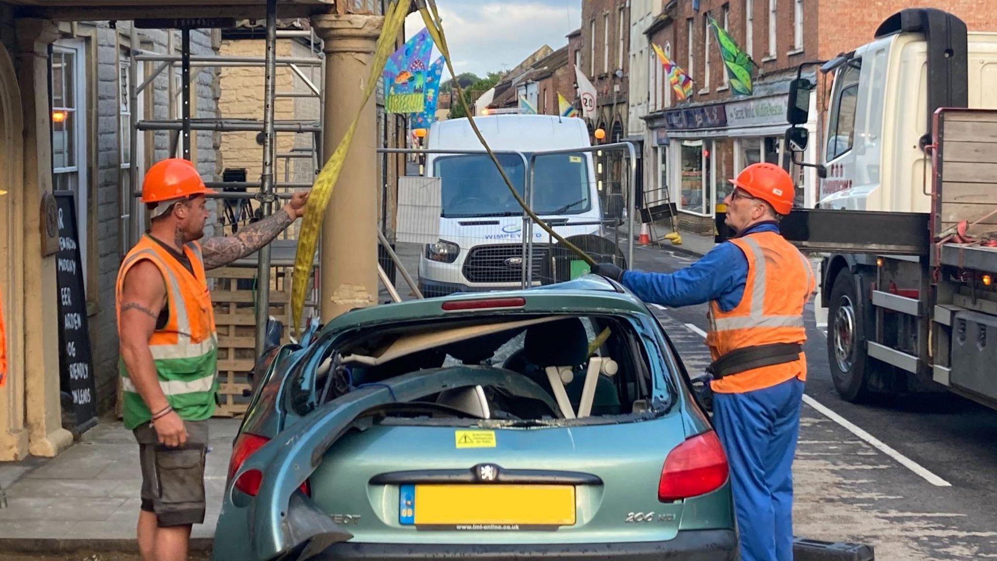 Image of two workmen helping to remove the green Peugeot