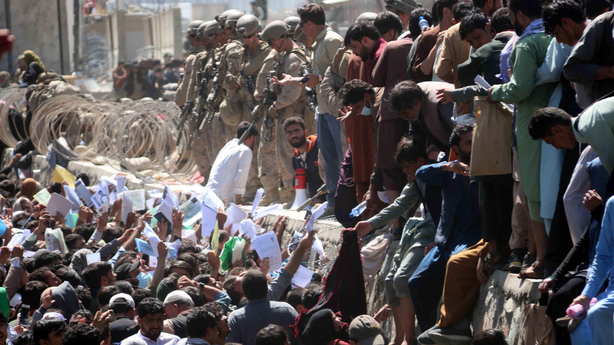 Afghans try to show their documents to soldiers outside Kabul airport