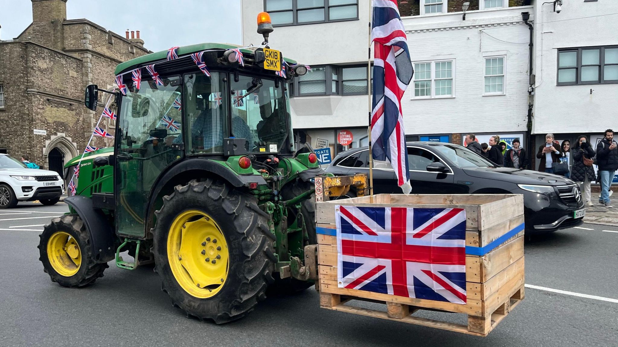 A tractor pulling an apple pallet, decorated with a union flag
