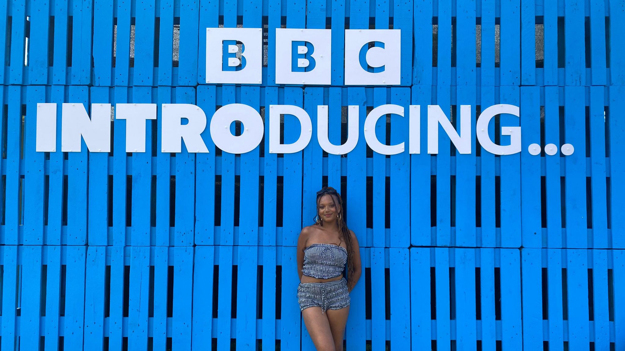 Tianna standing under a sign saying BBC Introducing with a completely blue backdrop