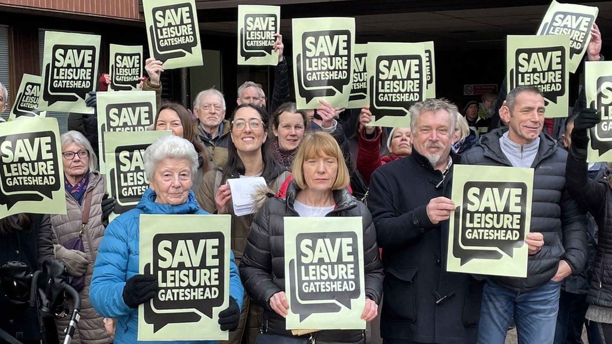 Protestors holding Save Leisure Gateshead placards stand outside the offices of Gateshead Council.