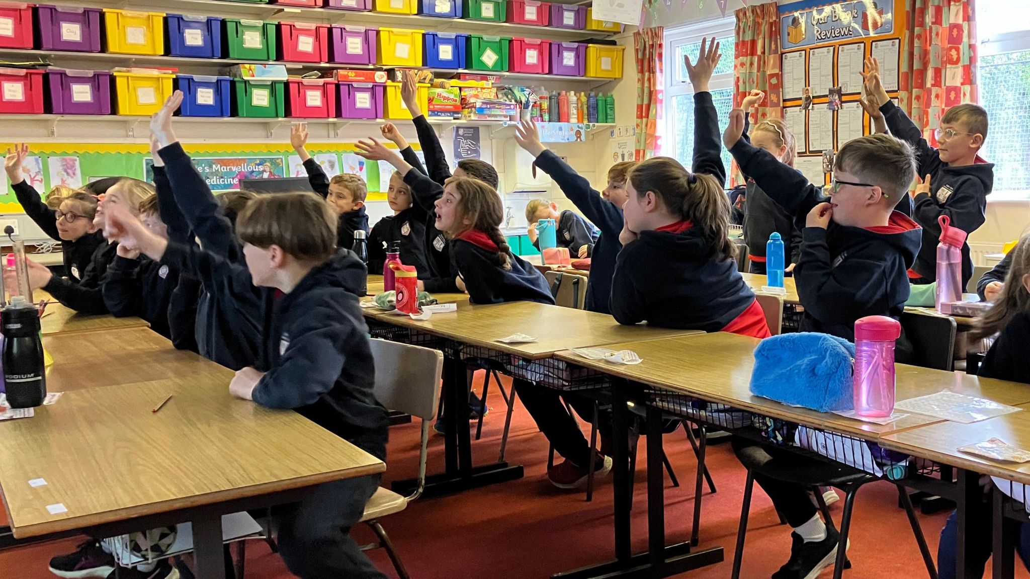 Pupils raising their hands in a classroom